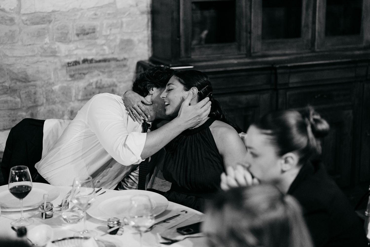 A black and white photo sequence showing a couple sharing an intimate moment at a dining table.