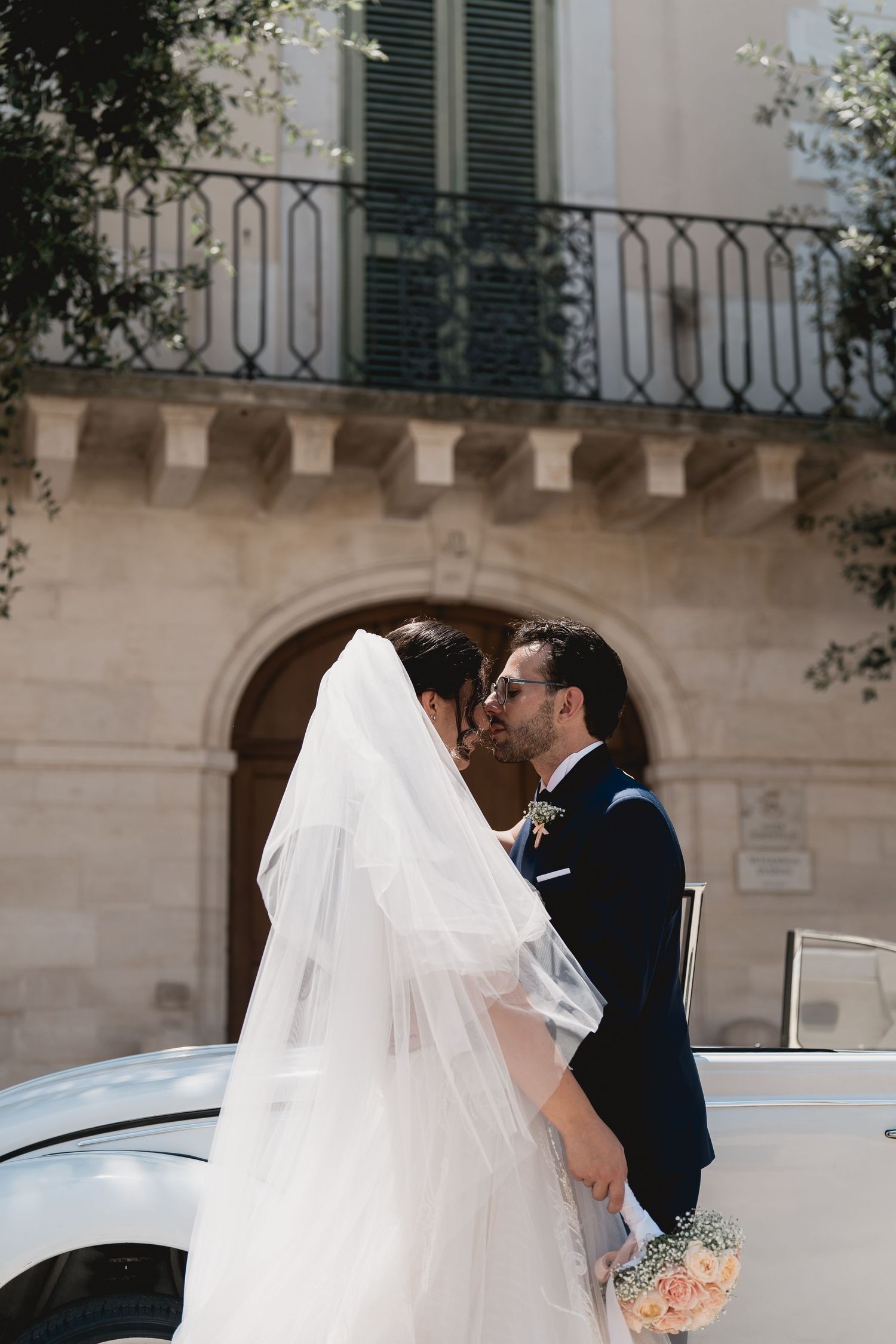 Classic vintage convertible carries newlyweds in elegant wedding attire.