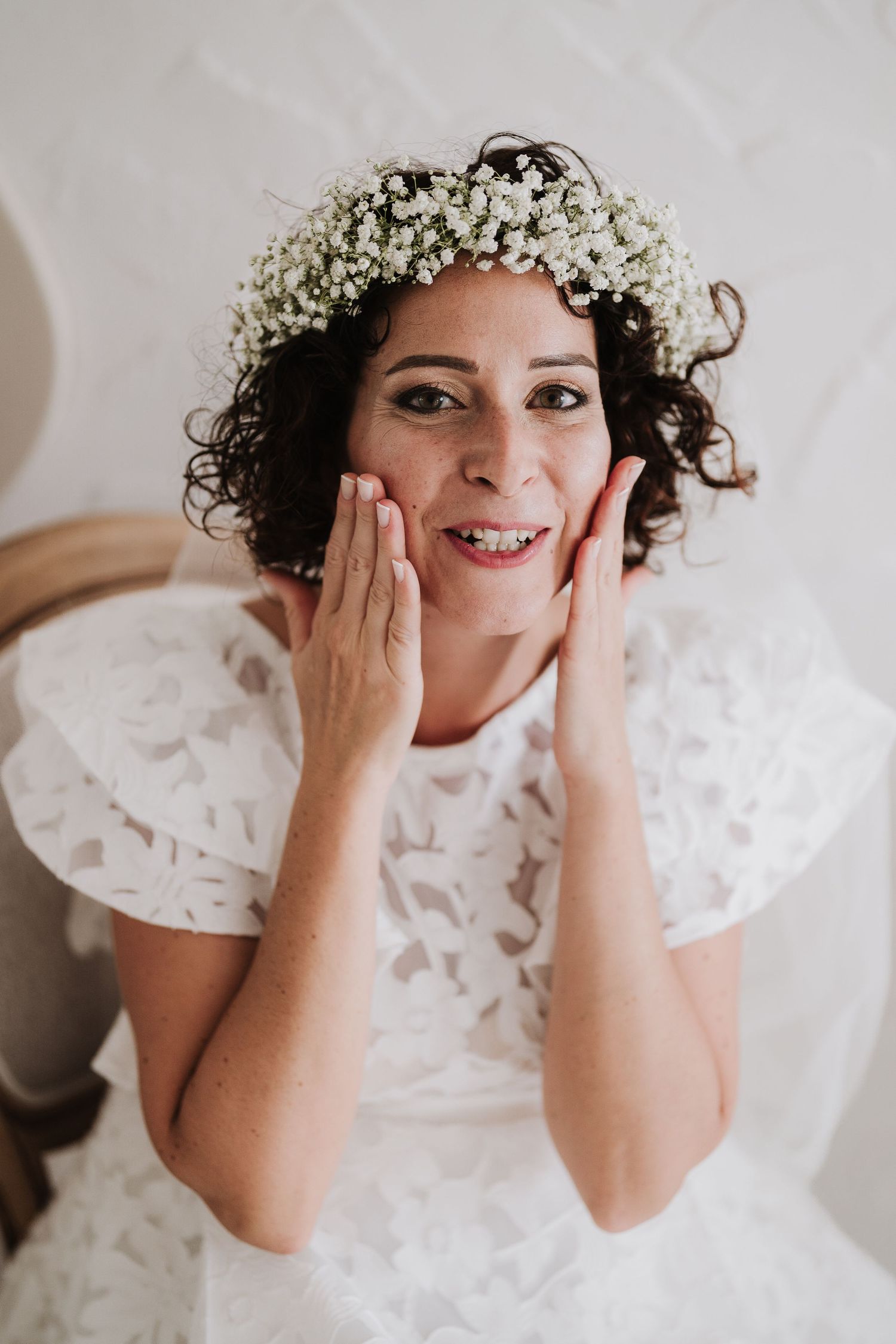 A joyful bride wearing a white floral crown and lace dress.