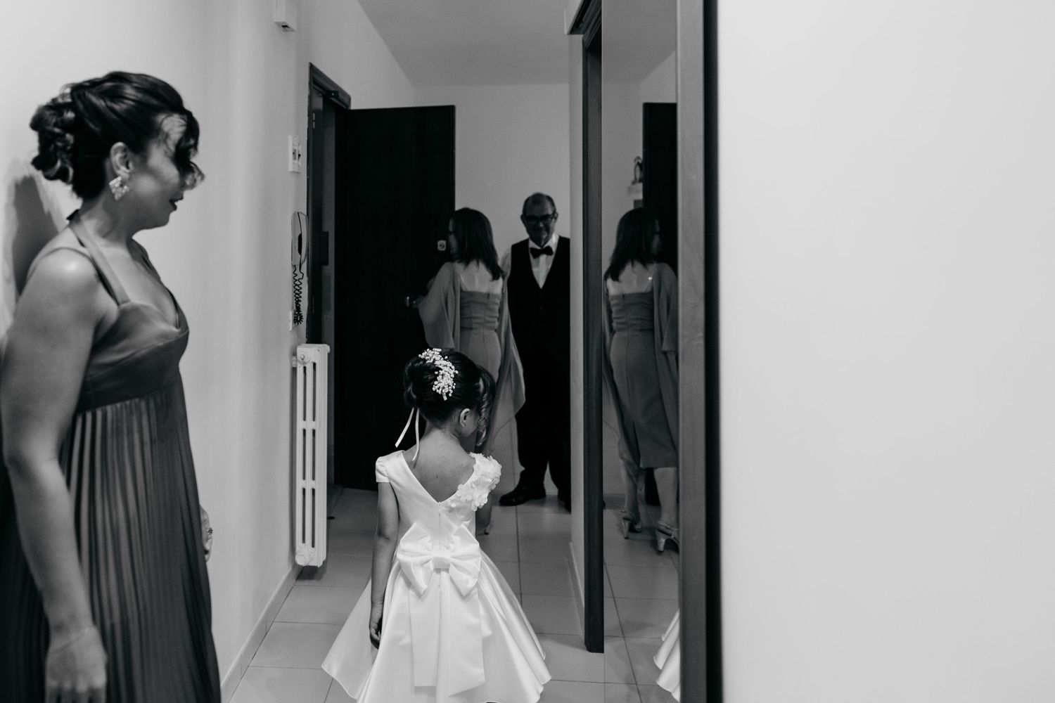 Black and white image of formal-dressed people walking down a hallway.