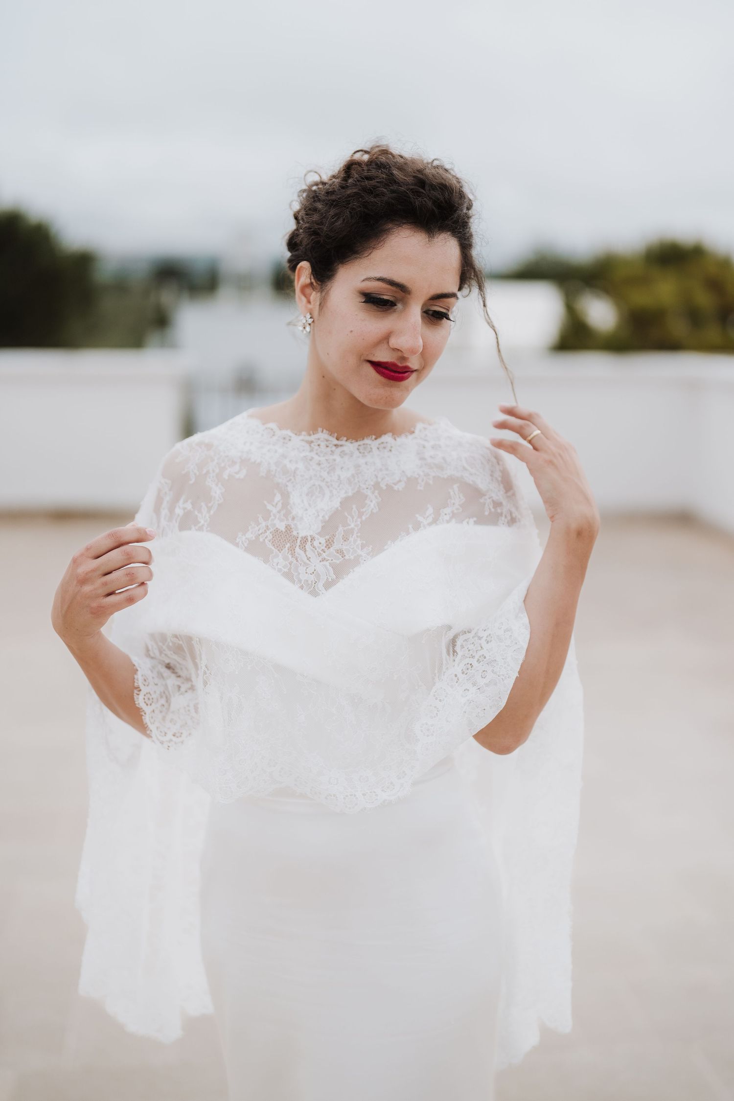 Close-up portrait of a bride wearing an elegant lace-detailed wedding dress on a terrace.