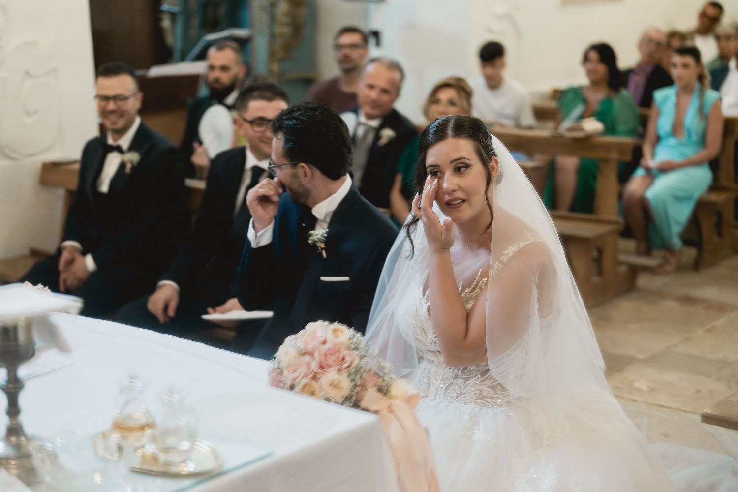 An emotional moment during a wedding ceremony in an elegant church with ornate white walls.
