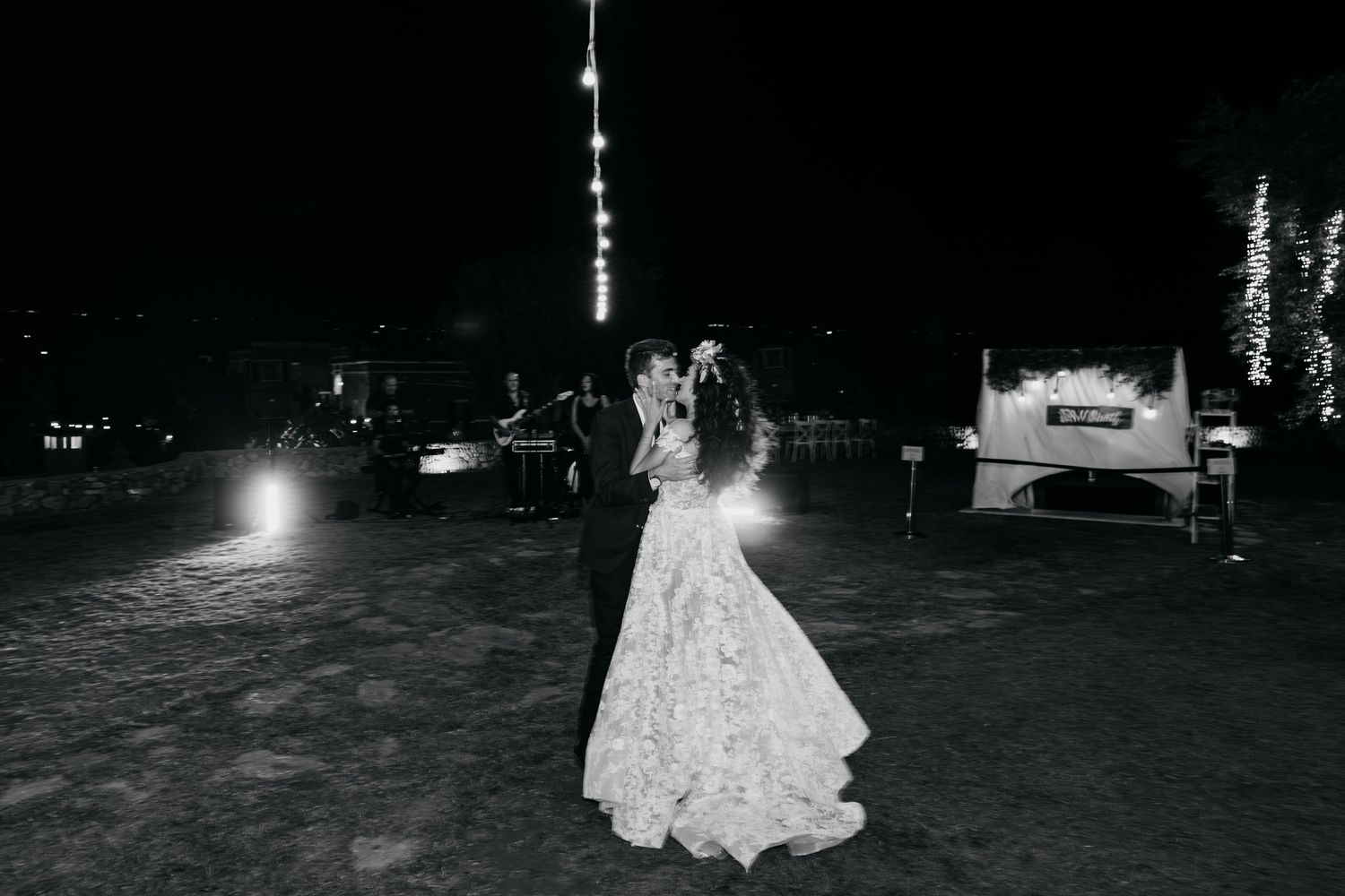 A wedding dance party under string lights at night with guests celebrating on an outdoor dance floor.