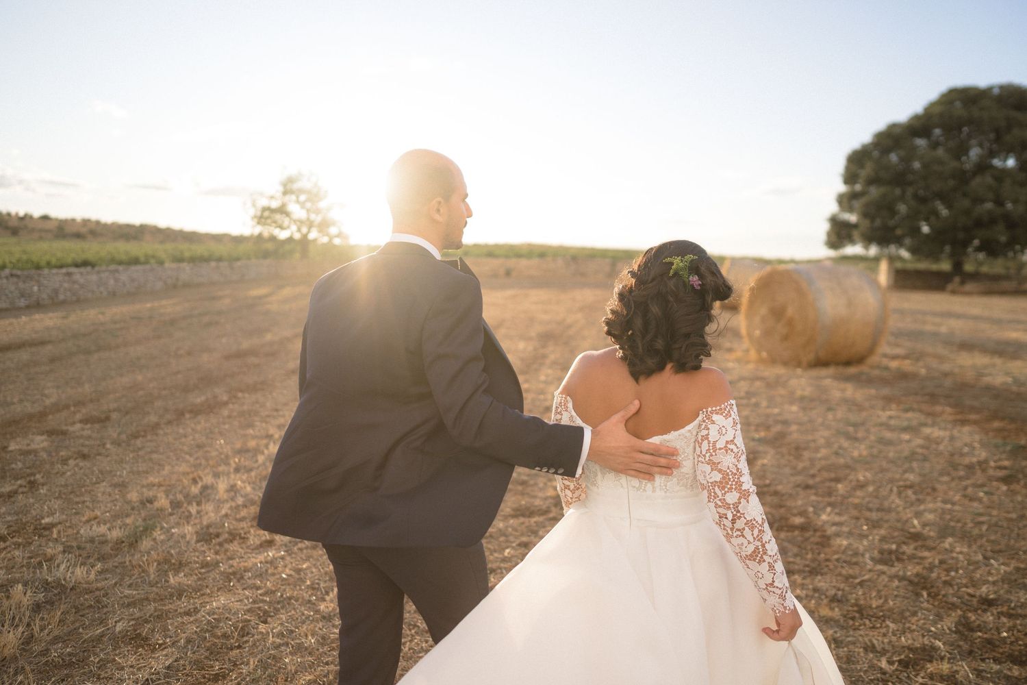Romantic sunset silhouette of newlyweds in a golden field during their wedding photoshoot.