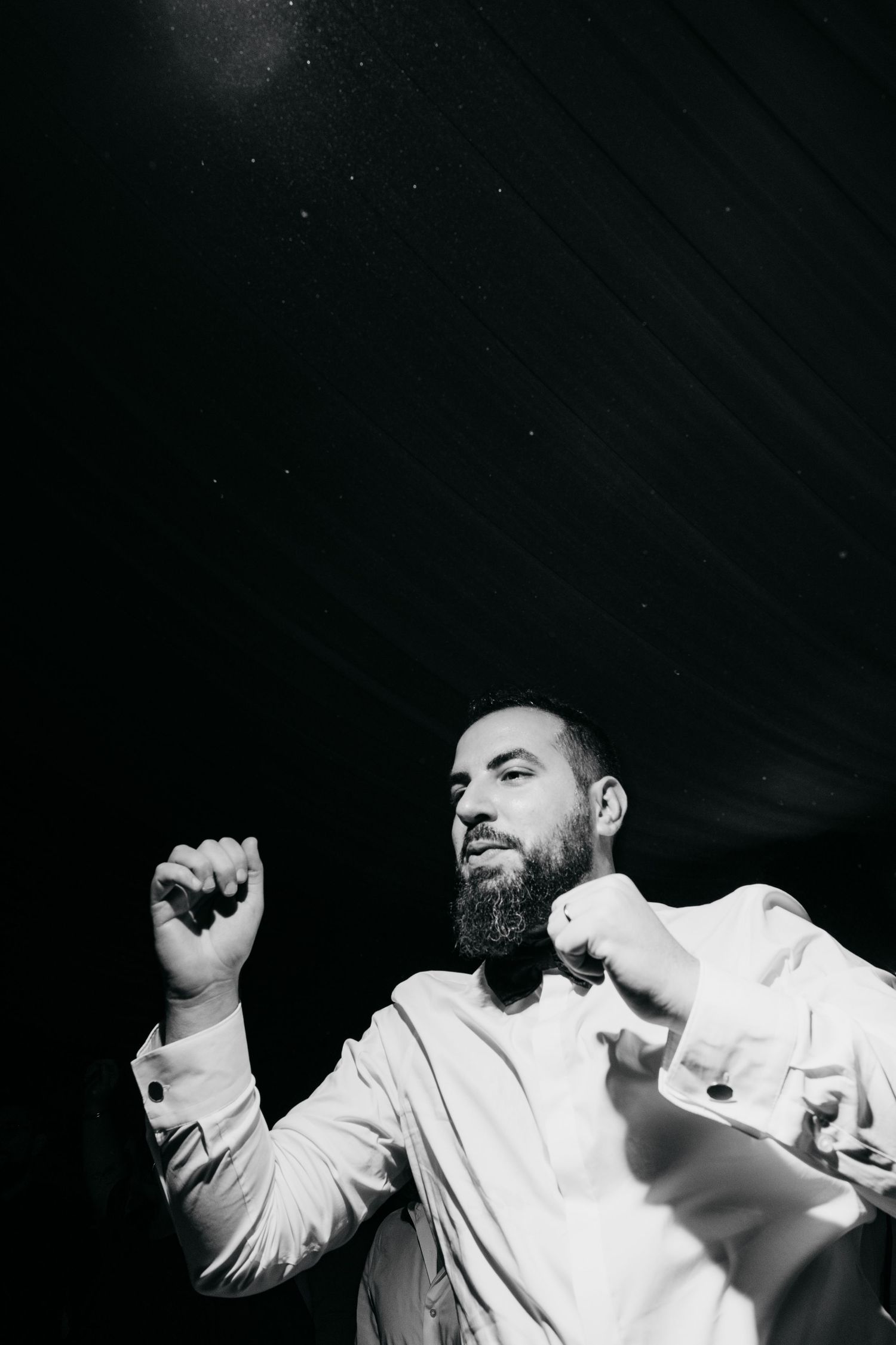 Black and white photos capture energetic dance moves at a wedding reception.
