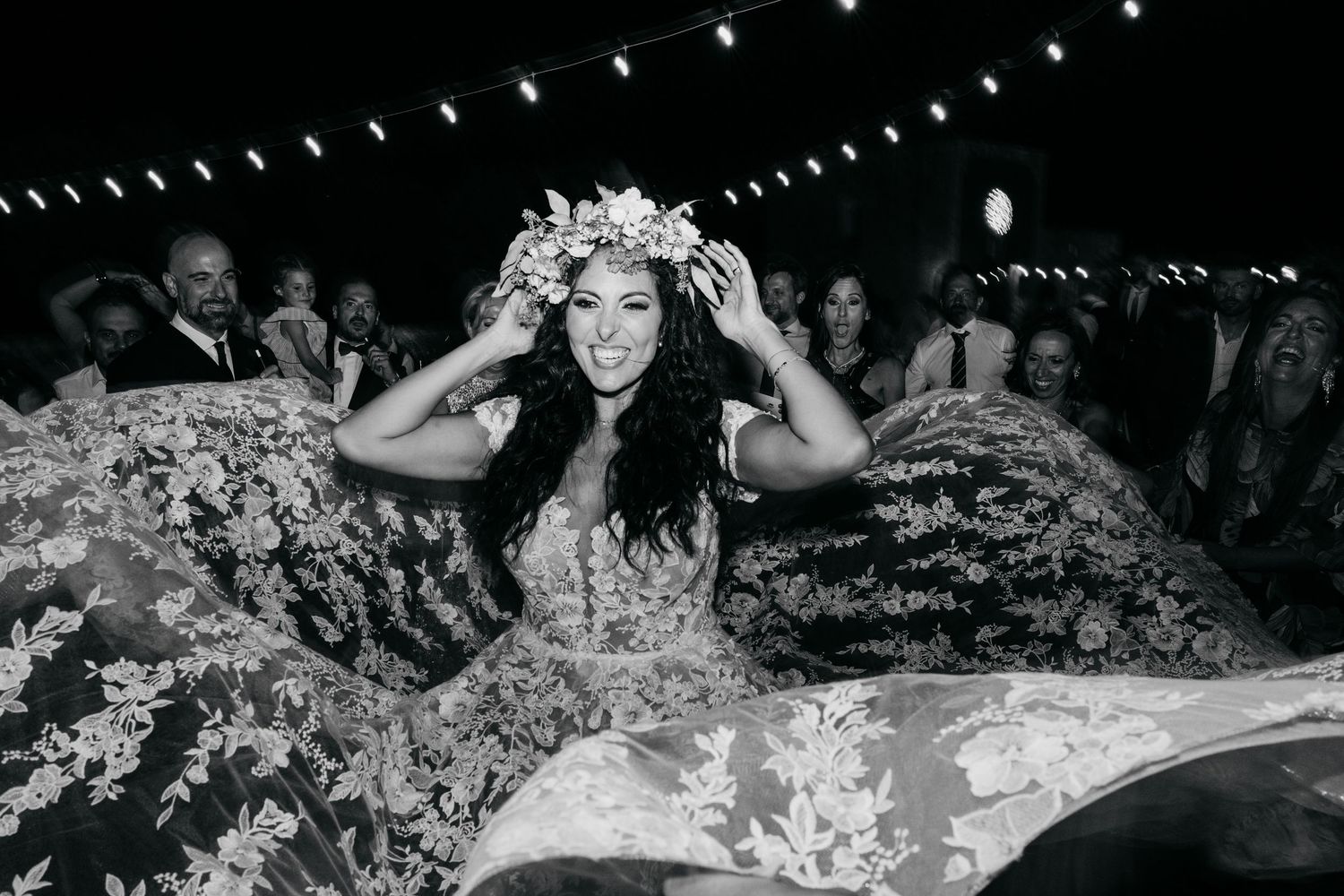 A joyful moment at a celebration with string lights overhead and a flowing floral dress.
