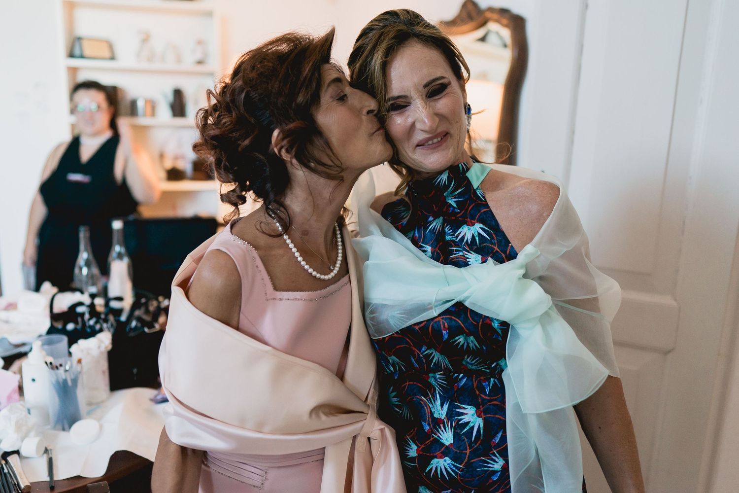 Two guests share an affectionate moment during wedding preparations.