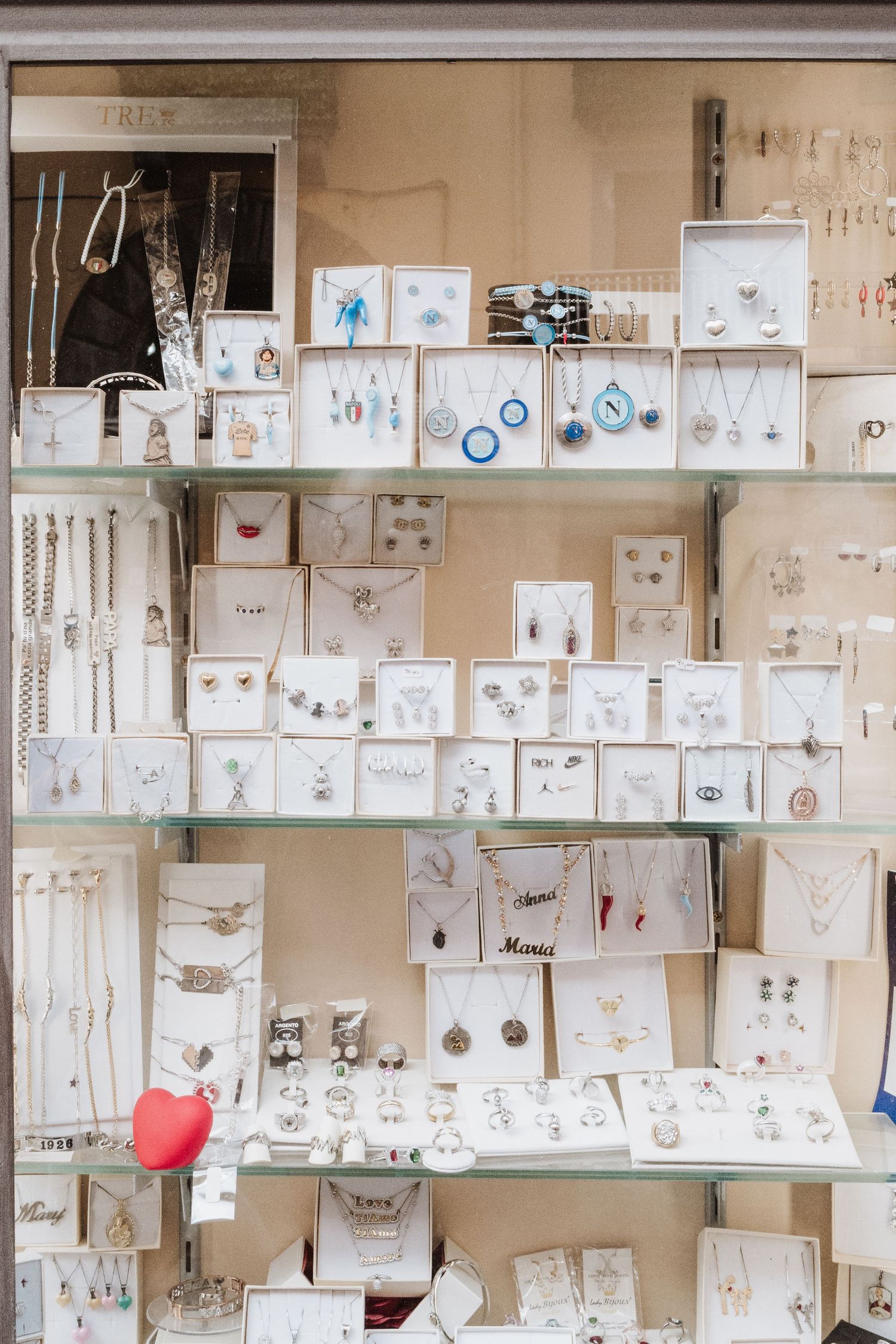 Display case filled with delicate jewelry and accessories arranged neatly on white display boards.