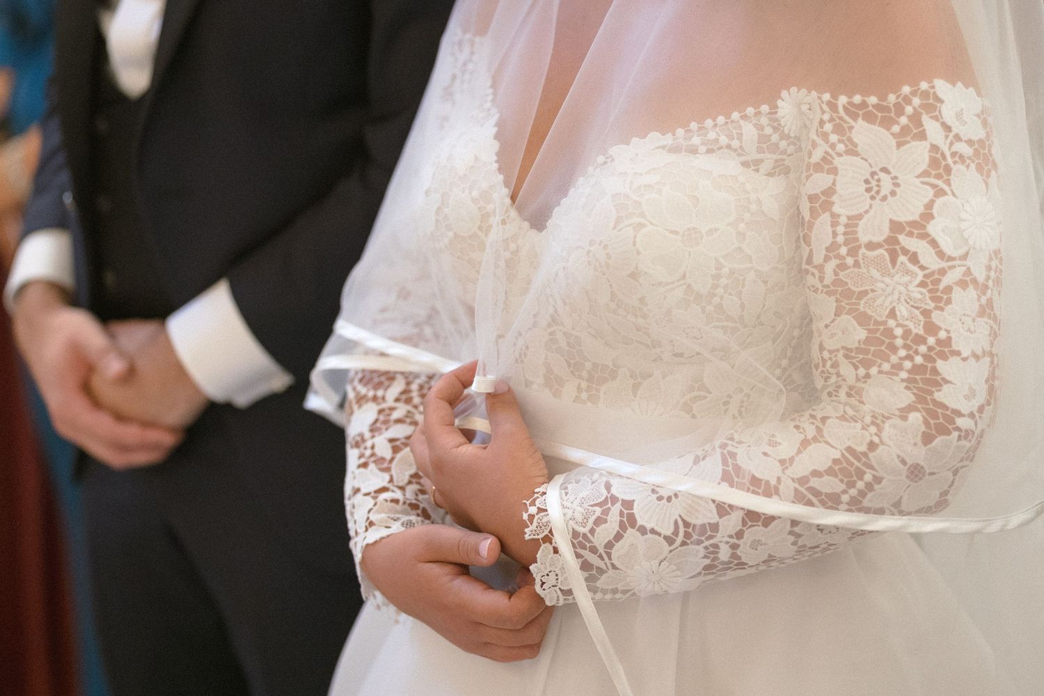 Detail shot of delicate lace wedding dress bodice with intricate embroidery.
