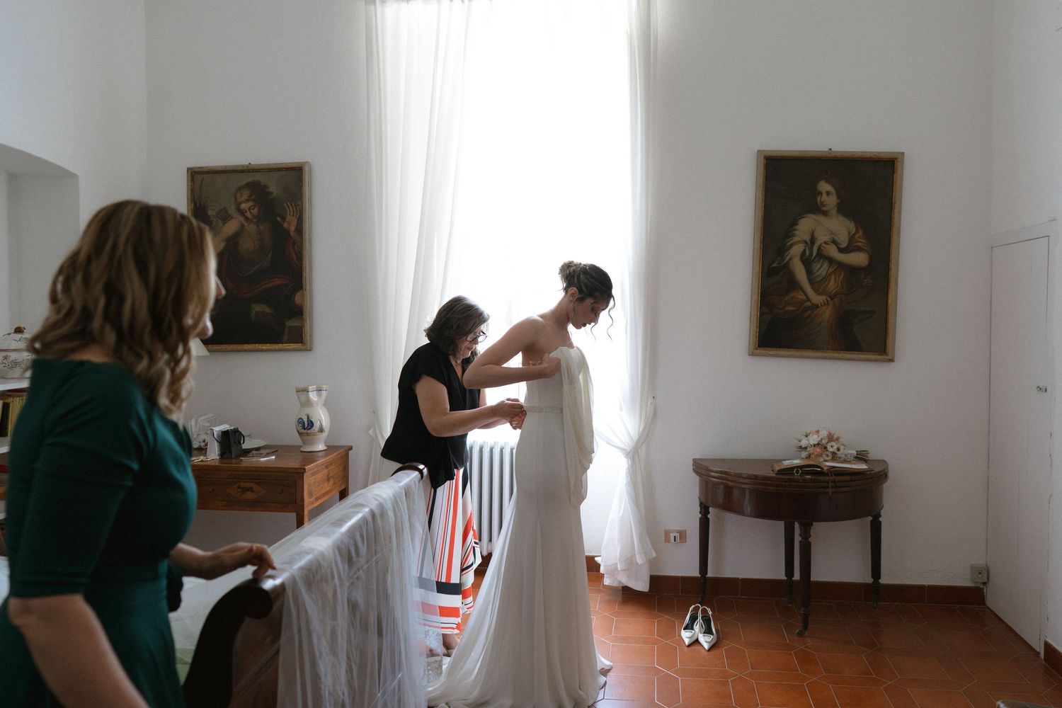 Interior room scene showing preparations with white fabric draping and classical paintings on the walls.