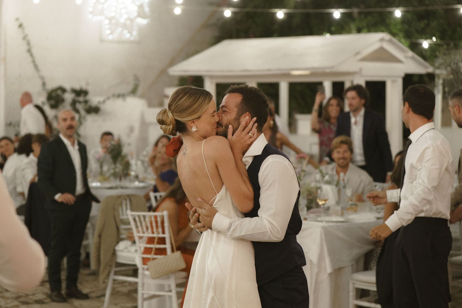 A romantic moment shared between newlyweds during their outdoor evening reception.