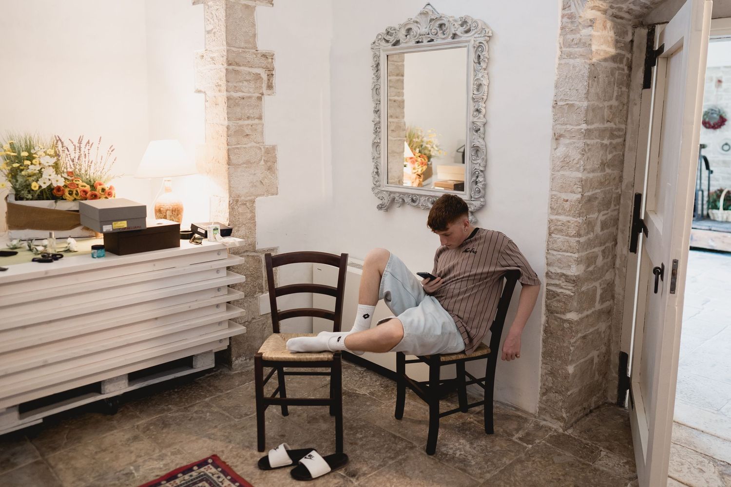 A quiet getting ready moment in an elegant stone-walled room with an ornate mirror.