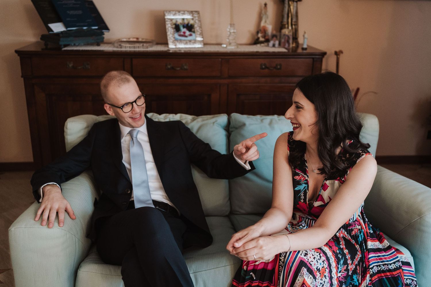 Casual conversation between guests on couch during wedding celebration.