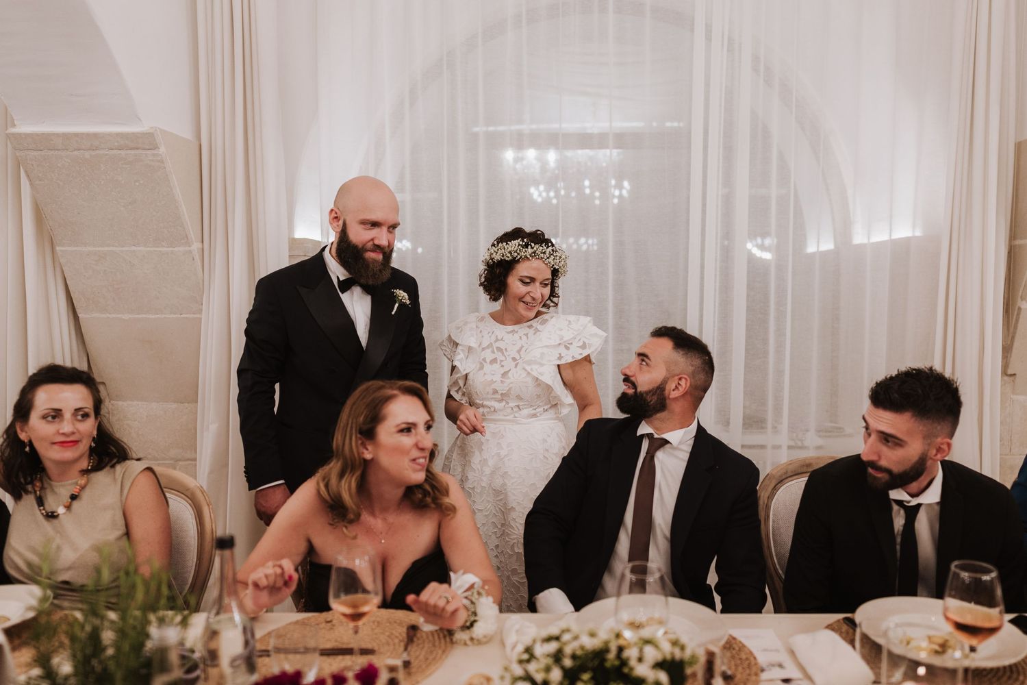 Wedding reception scene with guests seated at a decorated dinner table.