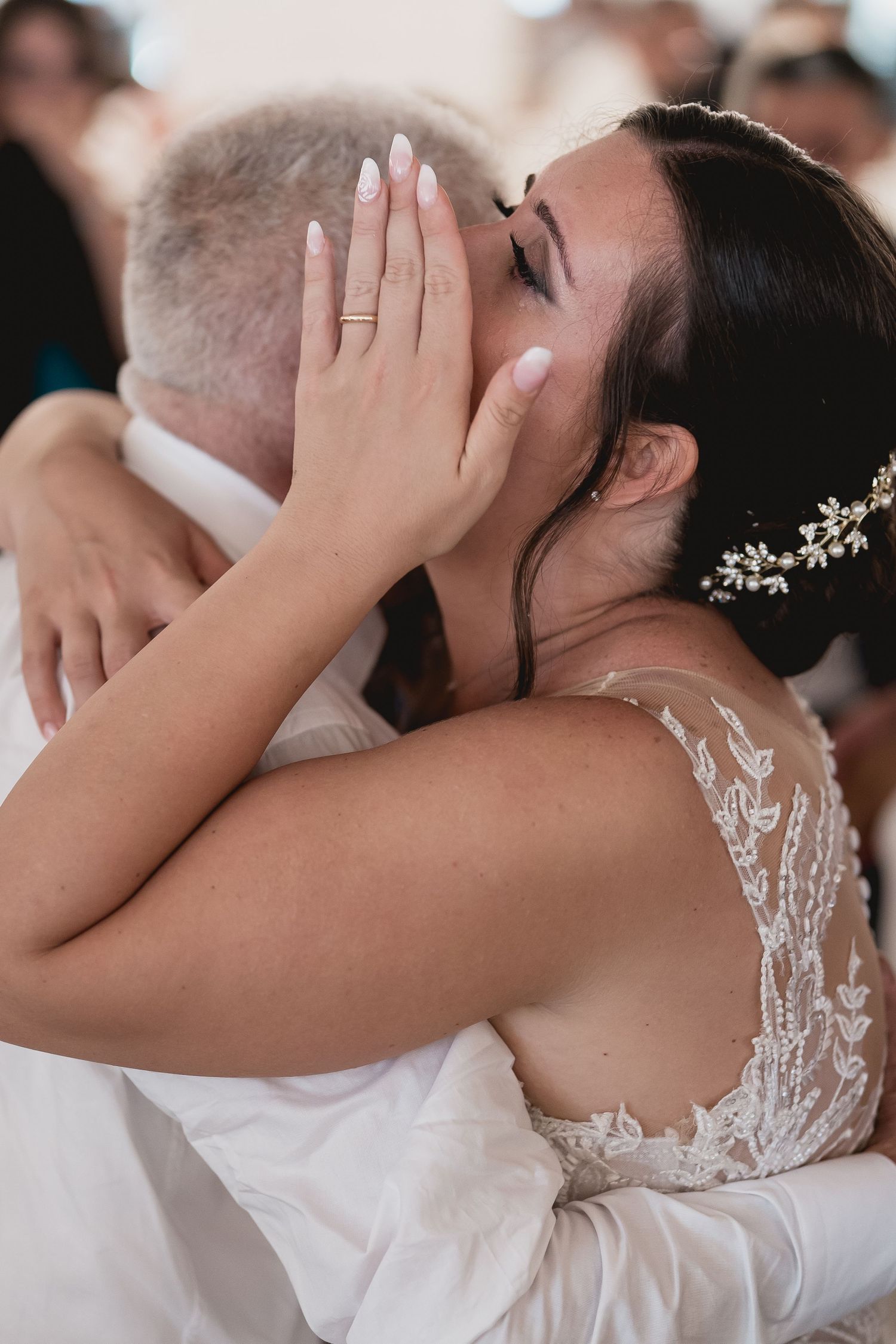 Emotional moment captured during wedding ceremony showing detailed lace dress.