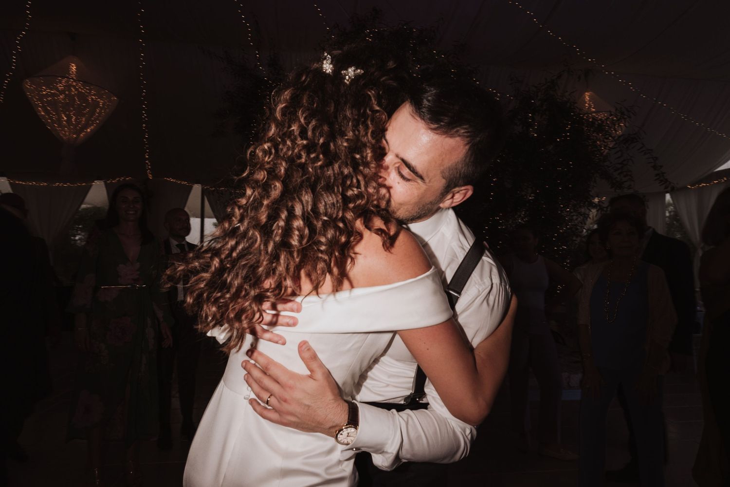 A tender moment between dancers at a dimly lit wedding reception.