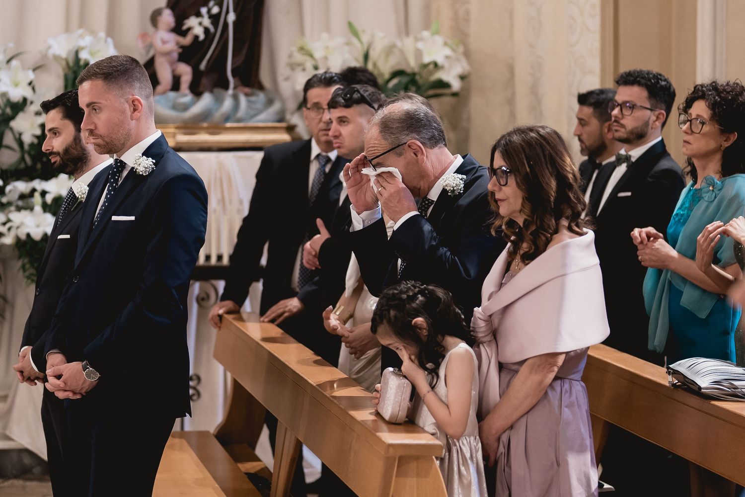 Wedding guests standing in church pews during an emotional ceremony moment.