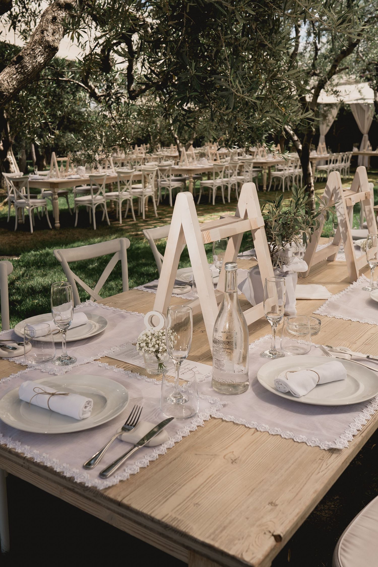 Elegant outdoor wedding reception table setup with rustic wood tables and white place settings.