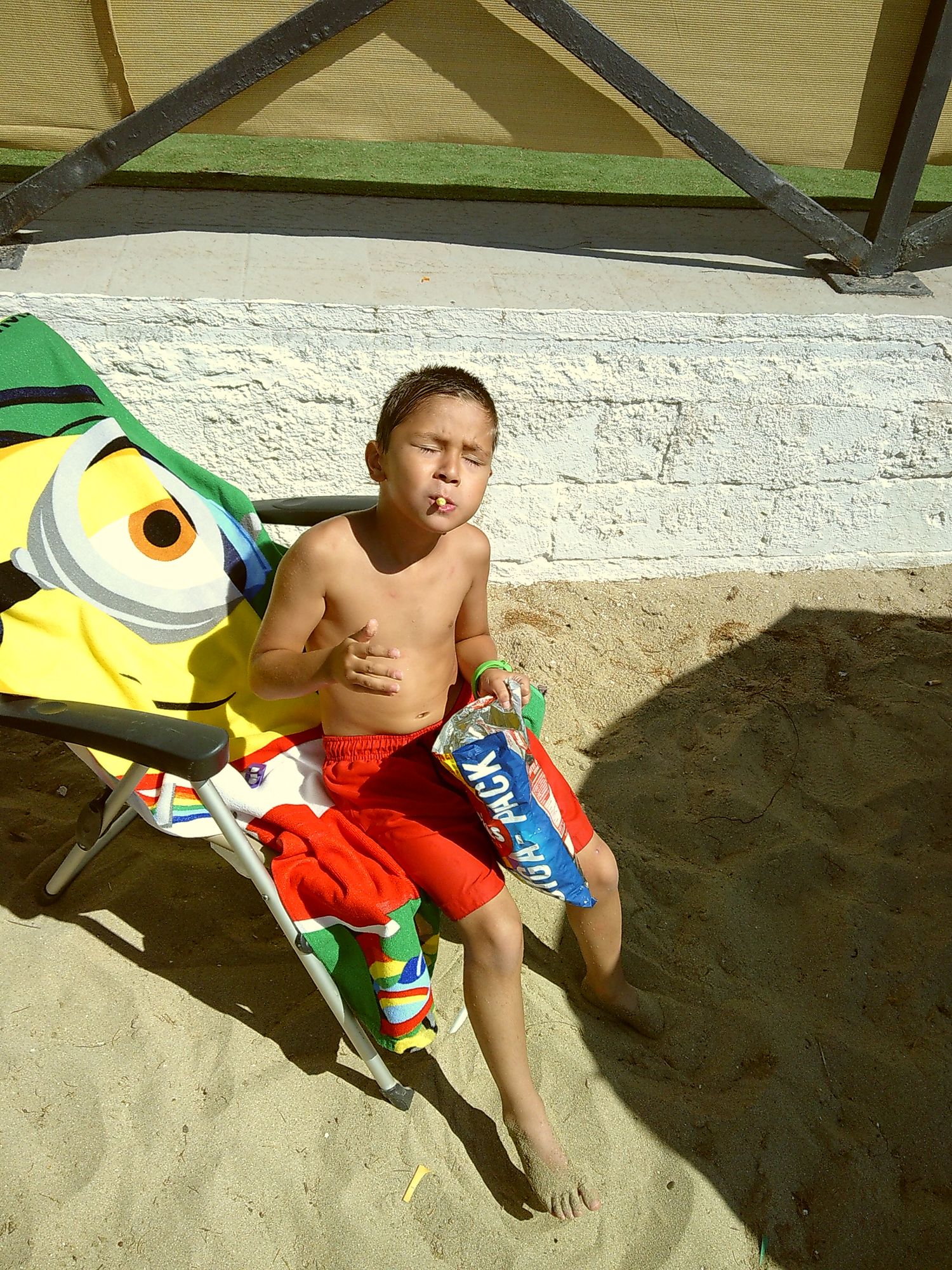A beach scene with a Minion character toy and someone relaxing on a beach chair.