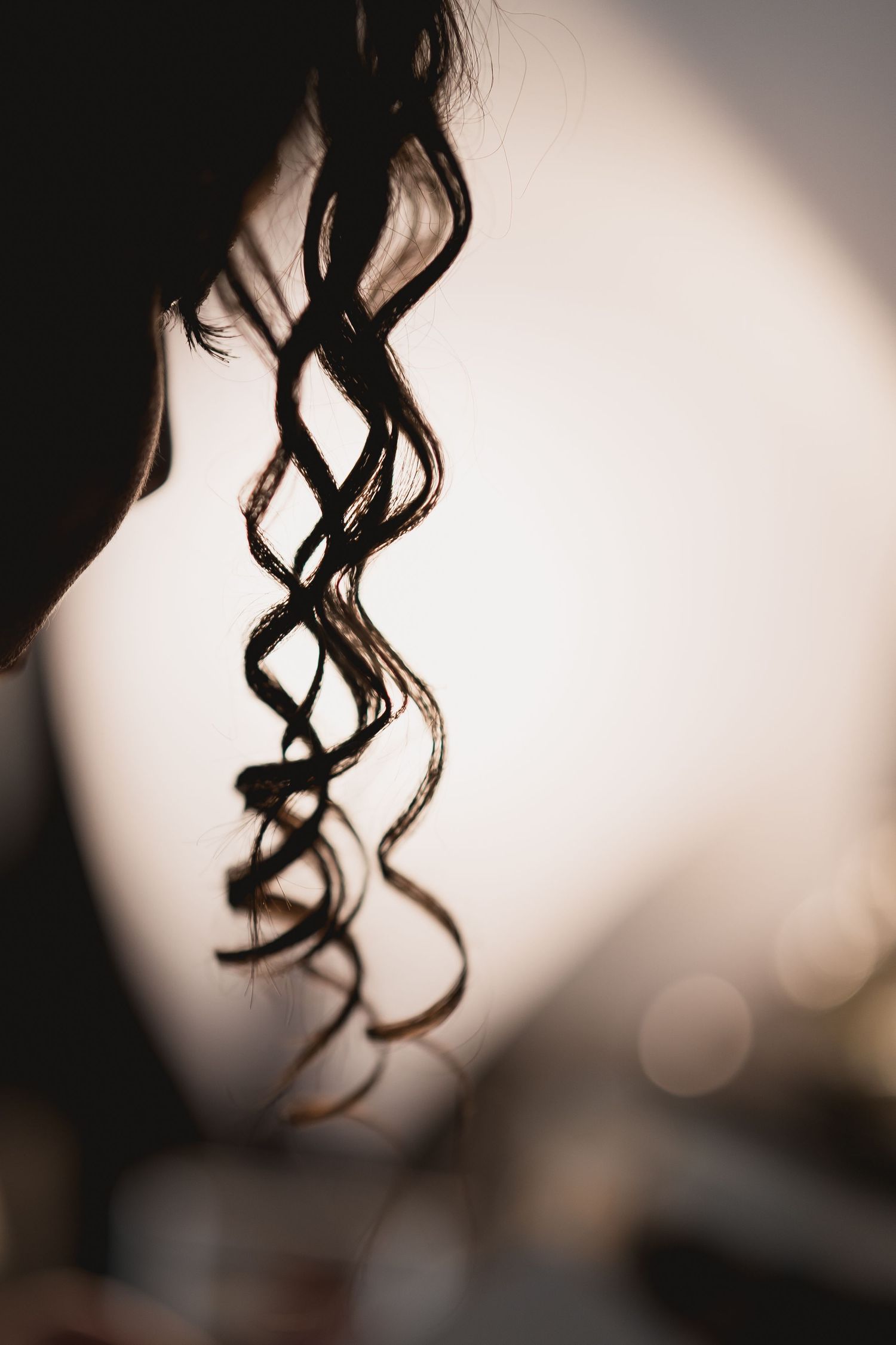 Artistic close-up of curled dark hair with dramatic lighting and shadows.