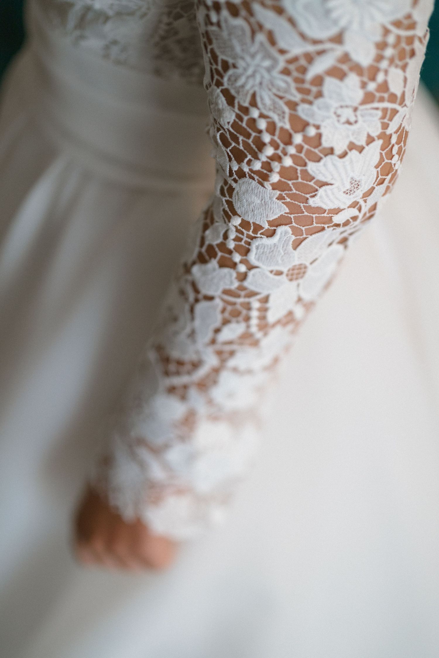 Detailed macro shot of delicate white lace pattern on a wedding dress sleeve.