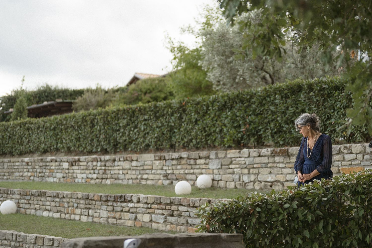 Stone wall landscaping borders a garden path with greenery.