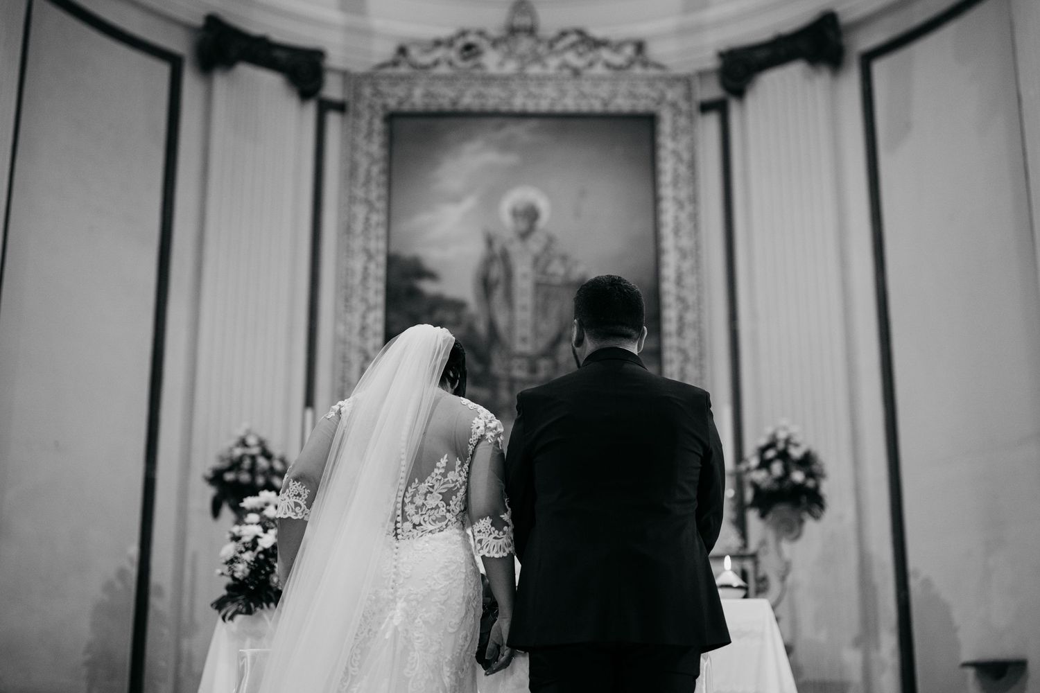Black and white photo of a traditional church wedding ceremony from behind.