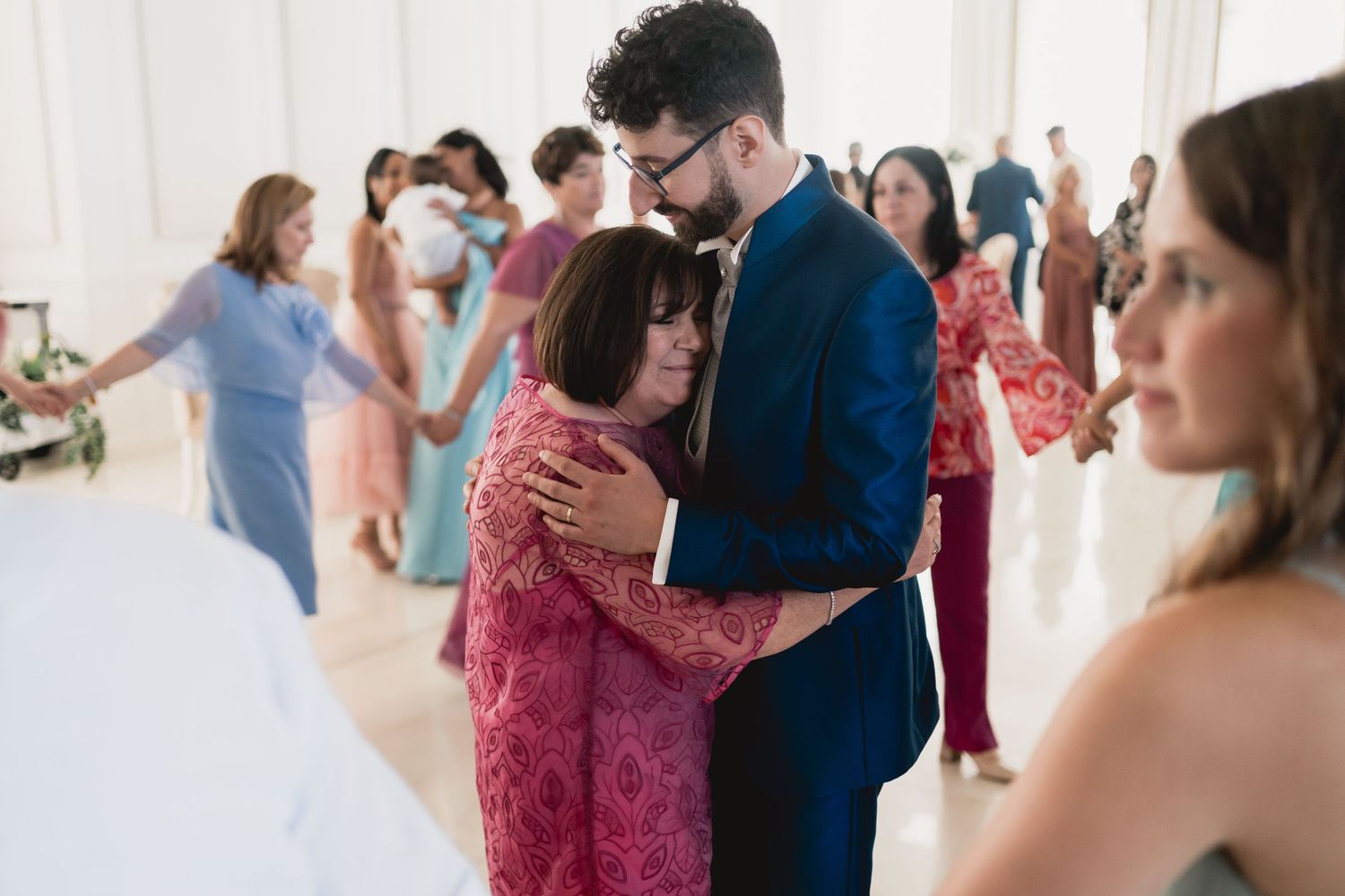 Guests share warm embraces during an emotional wedding reception moment.