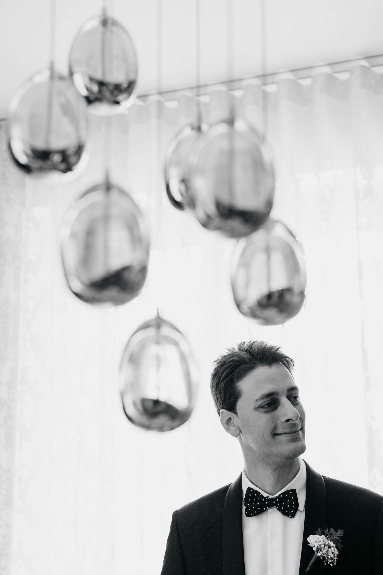 Modern reception venue with hanging glass globe lights and formal wedding attire.