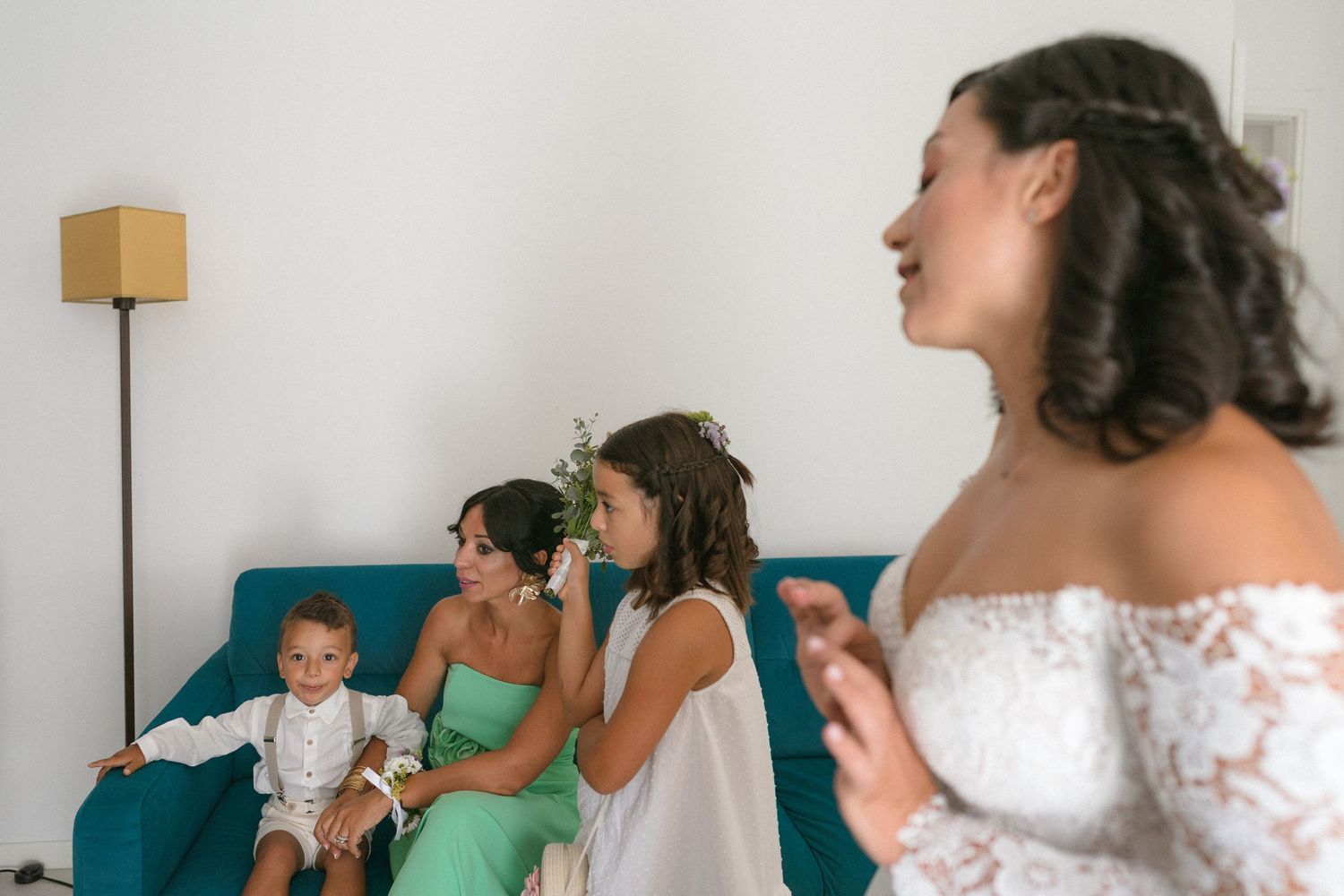 Bridesmaids in matching outfits gather together during wedding preparations in a bright room.