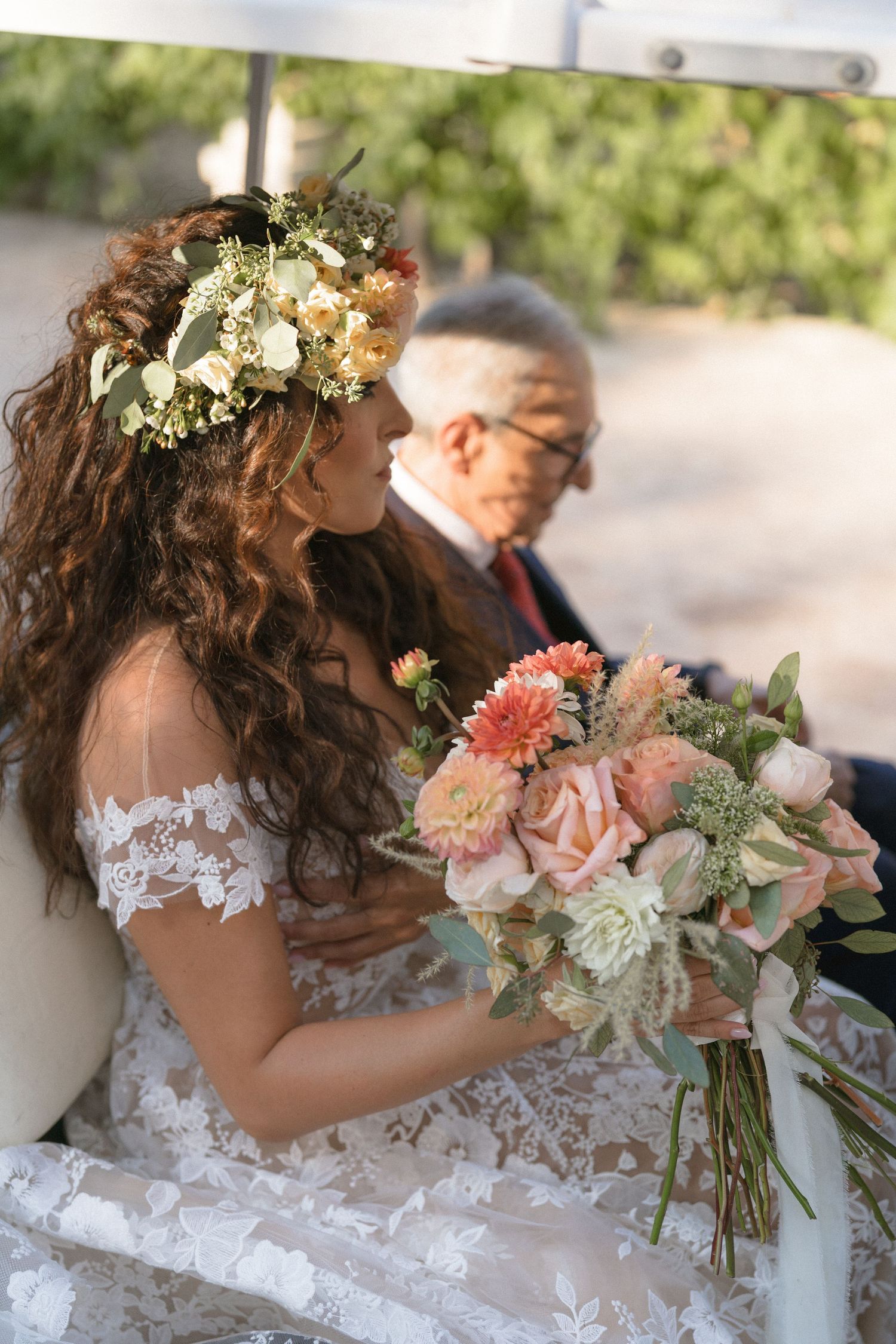 Person in lace wedding dress holding a romantic bouquet of pink and white flowers.