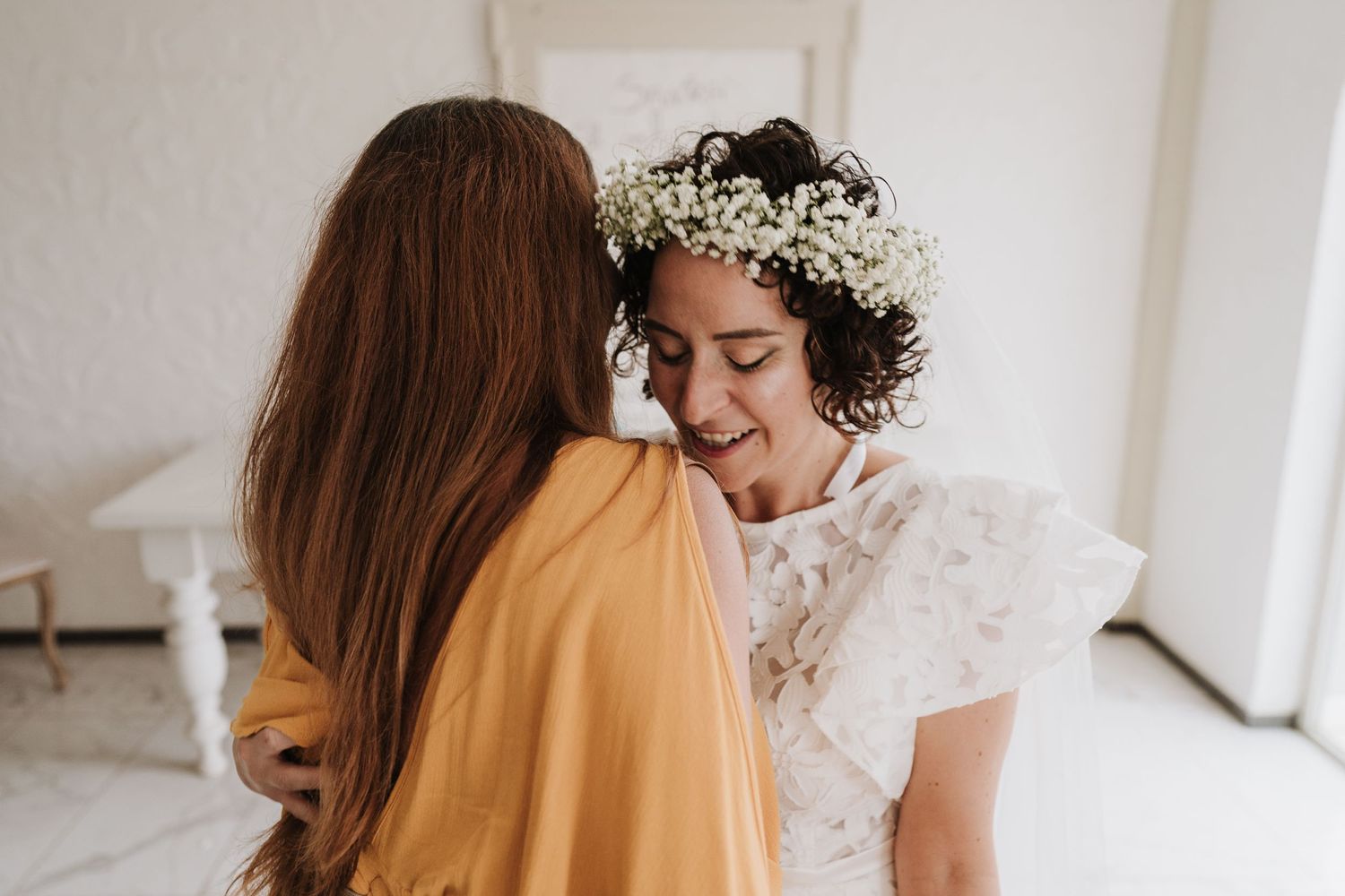 Joyful wedding moment between two people in a bright white room with natural light.