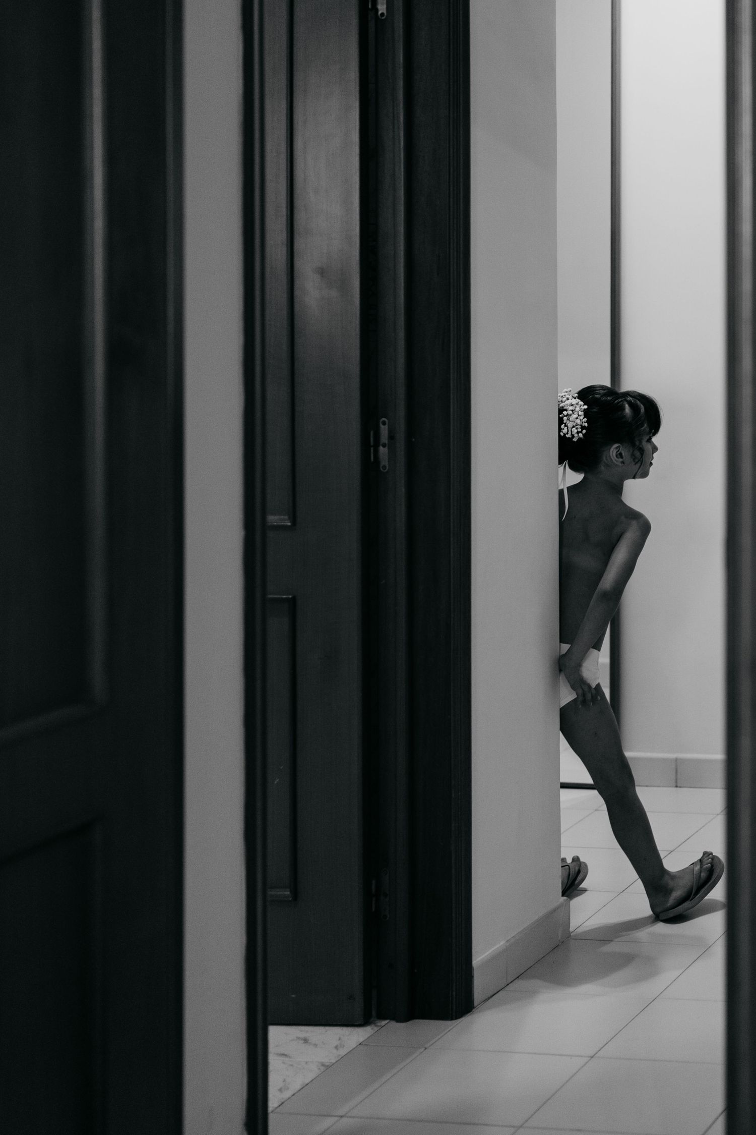 Black and white photo showing a silhouette walking past a doorway in a modern interior hallway.