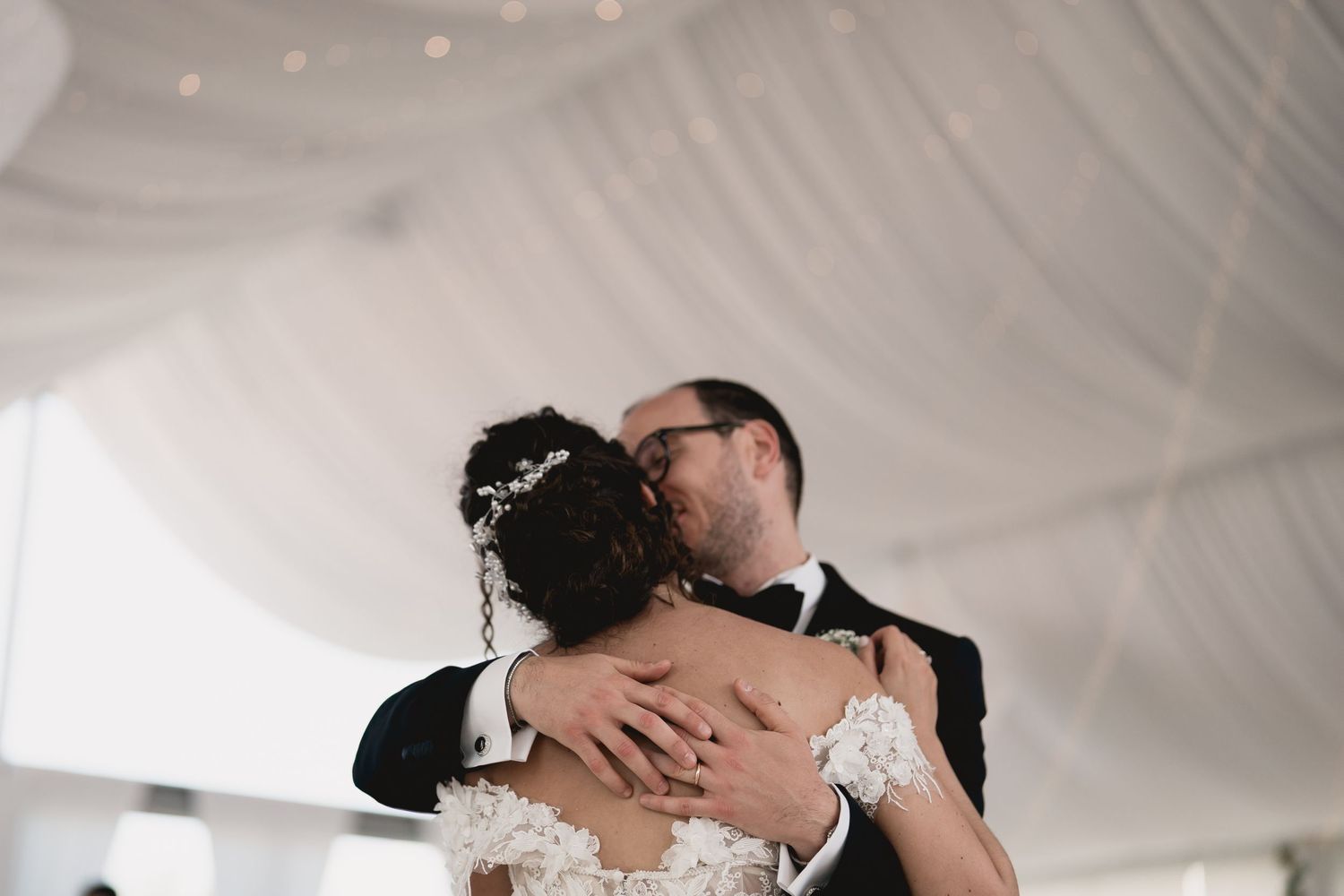 Intimate wedding dance moment under white fabric draped ceiling.