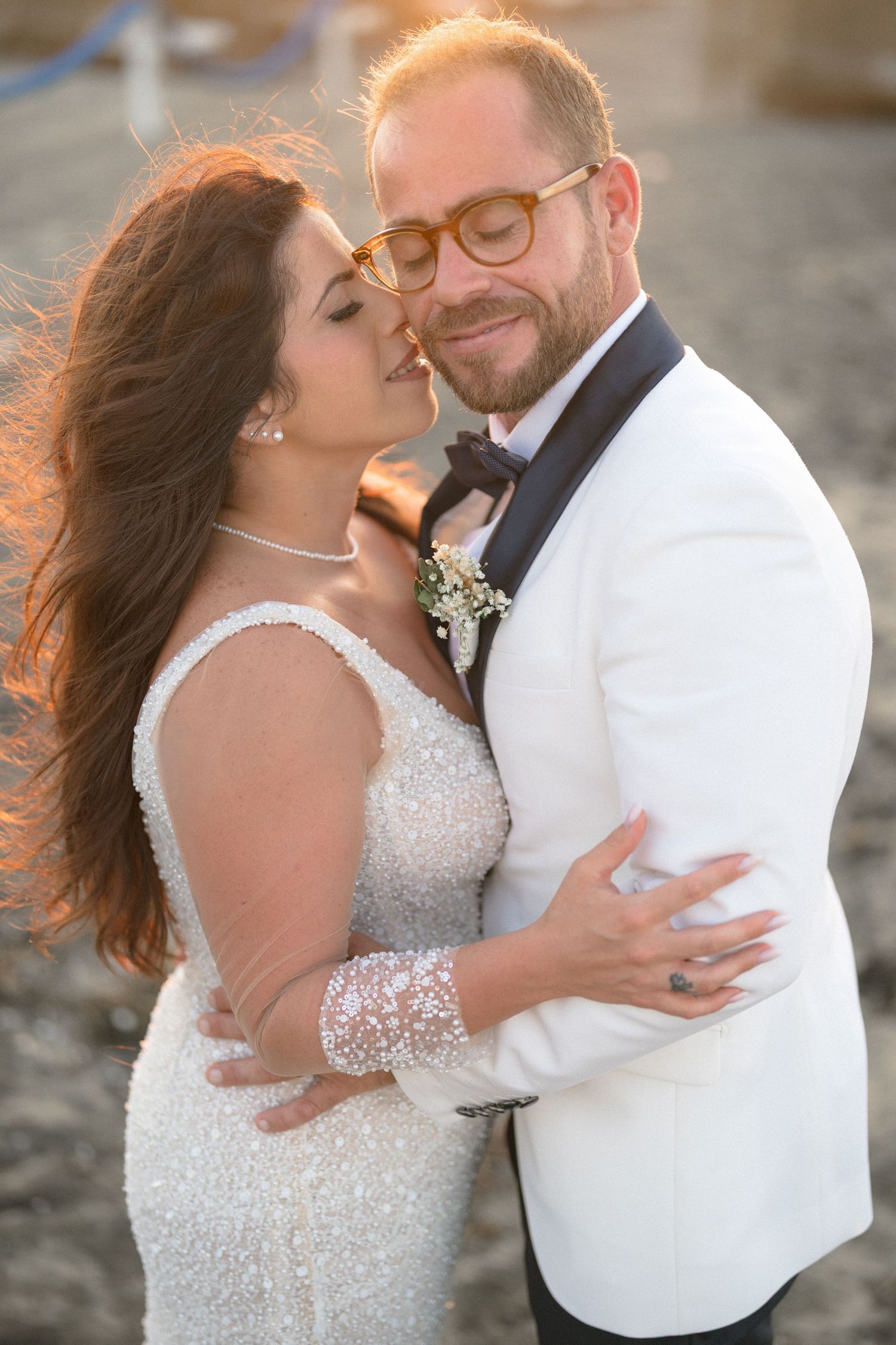 A romantic sunset beach wedding photoshoot featuring a sparkly white gown and white tuxedo jacket.