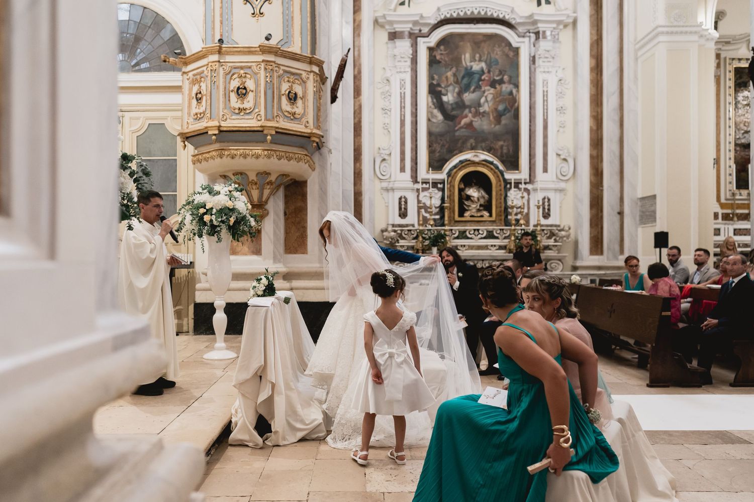 Wedding ceremony in ornate church with flowing white dress and architectural details.