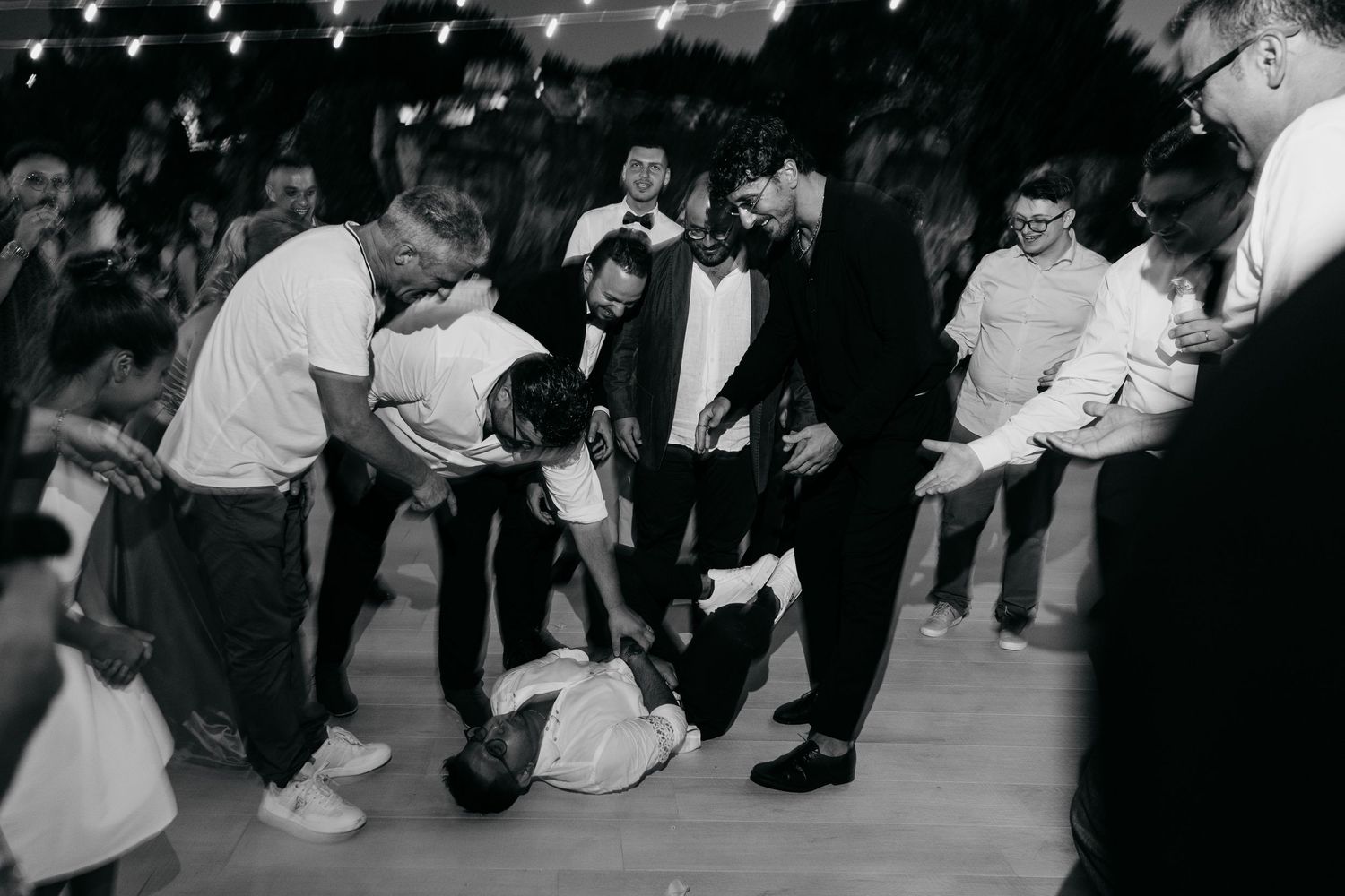A black and white vintage photo of people dancing energetically at a wedding reception.