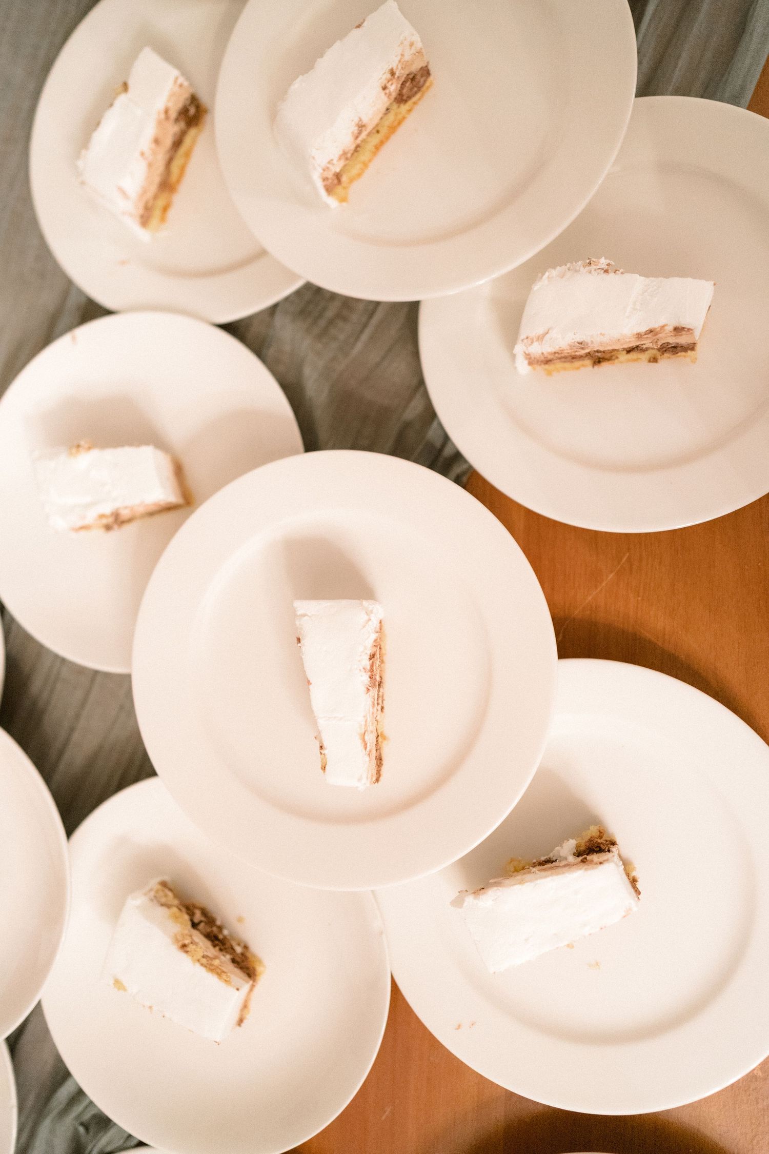 Overhead view of empty white dinner plates arranged on a wooden table.