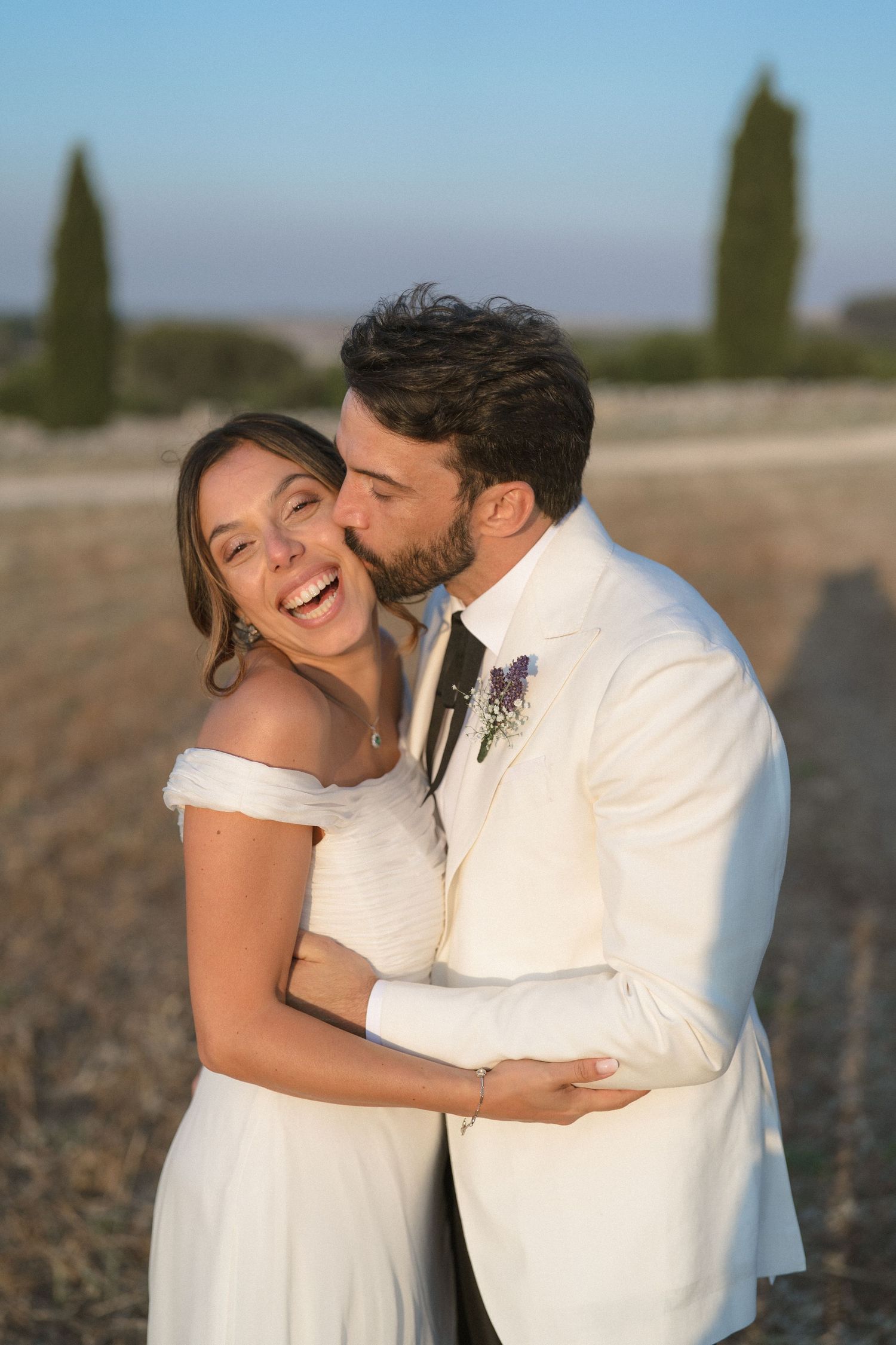 Romantic outdoor couple photoshoot showing joyful laughter and tender moments between newlyweds at sunset.