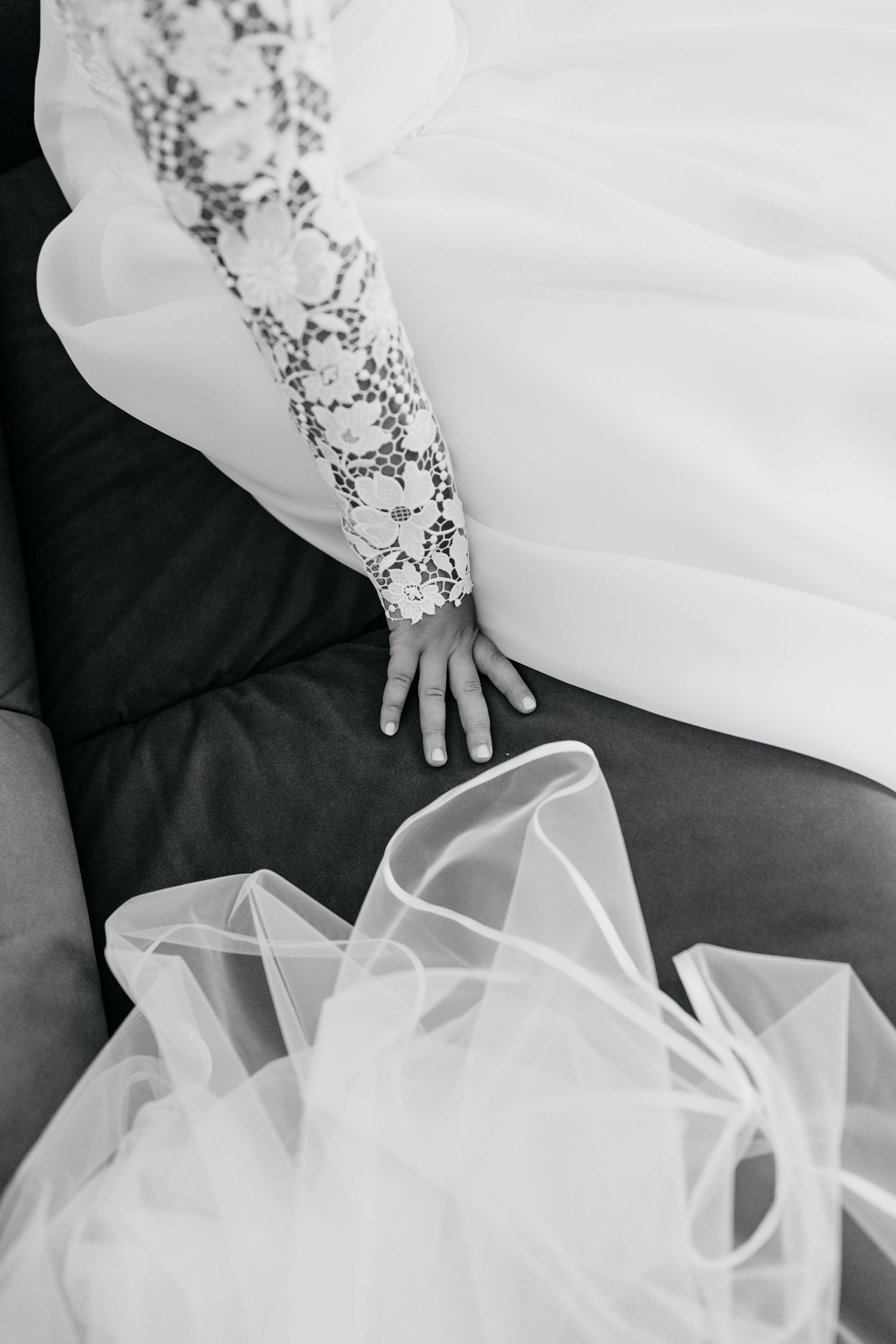 Close-up detail shot of delicate lace sleeves and flowing white tulle fabric from a wedding dress.