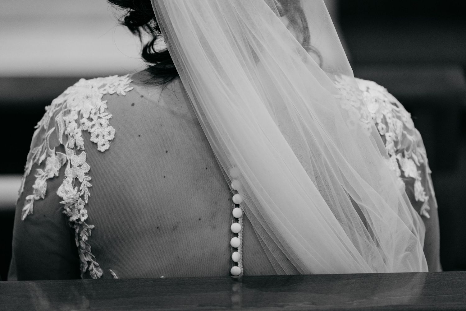 Close-up detail of delicate white wedding veil with lace trim in black and white photography.