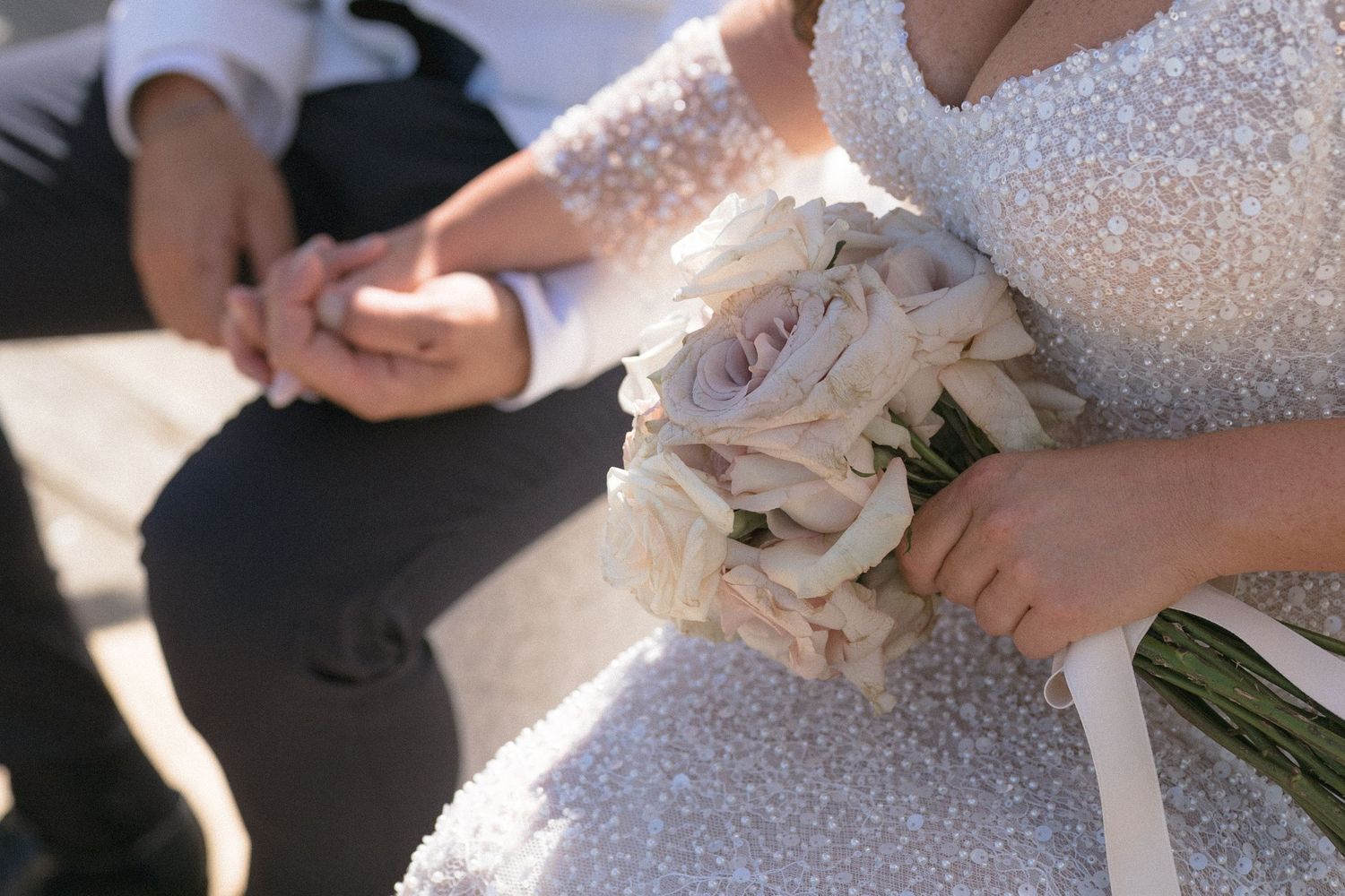 A sparkly beaded white wedding dress detail shown in an elegant close-up shot.