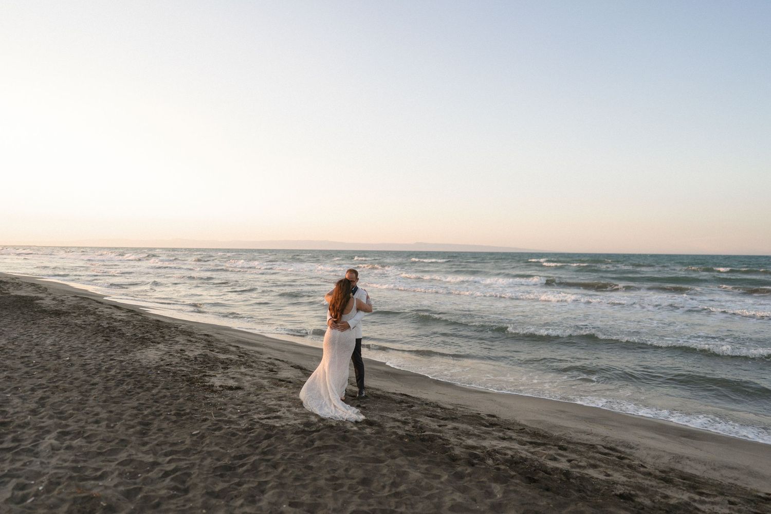 Romantic beach wedding silhouettes against a sunset ocean backdrop.