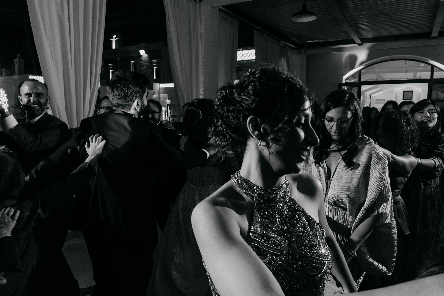 Guests dance and celebrate at elegant black and white nighttime wedding reception under outdoor canopy.
