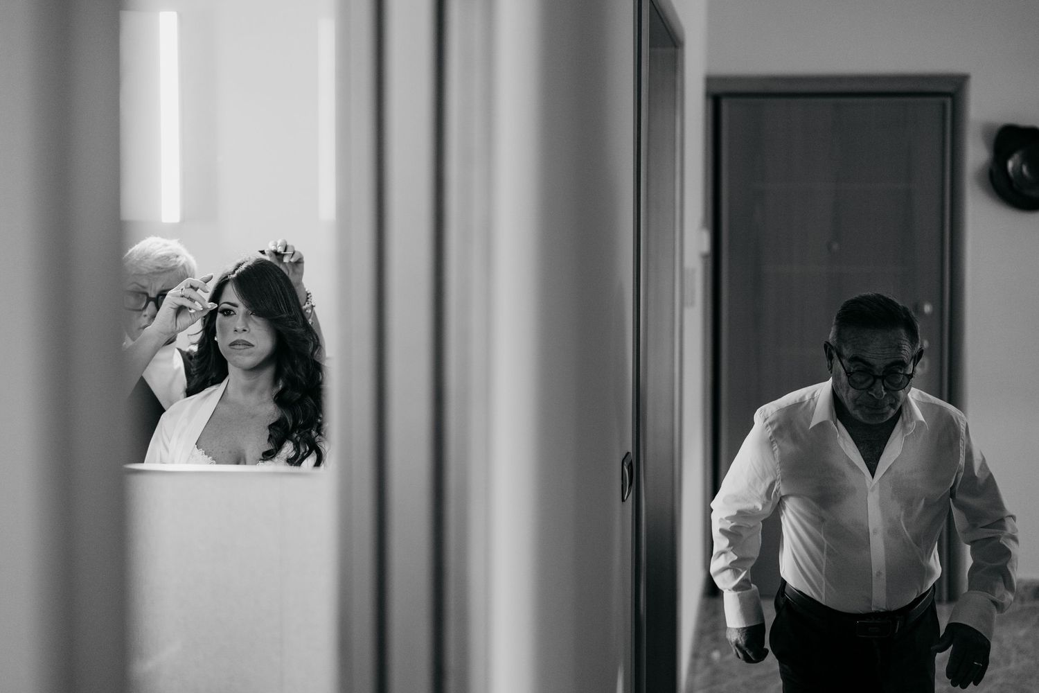 Black and white candid wedding moments captured in a hallway sequence.