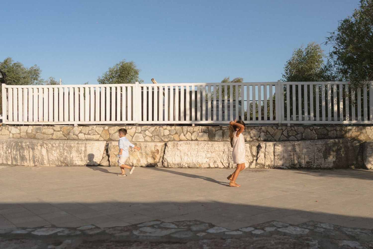 Empty outdoor terrace with white railing and stone wall during daytime.