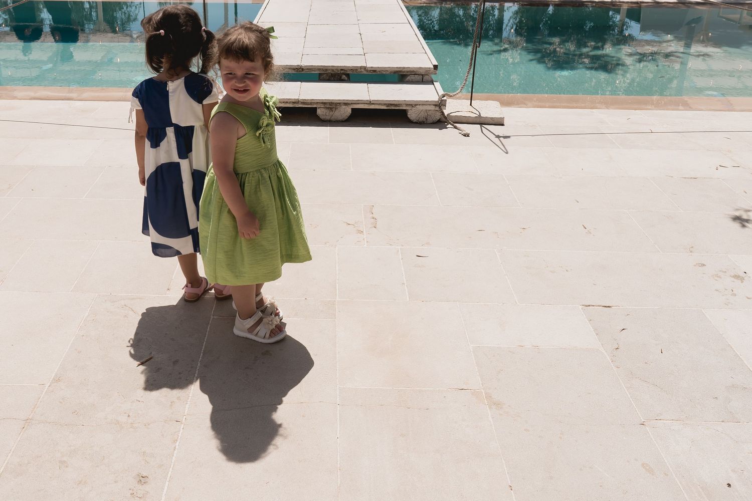 Children in formal attire playing by poolside at outdoor event.
