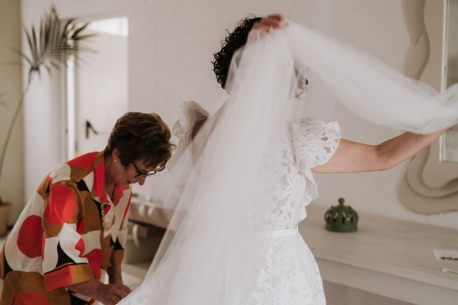 Wedding dress preparation scene with delicate lace details being adjusted.