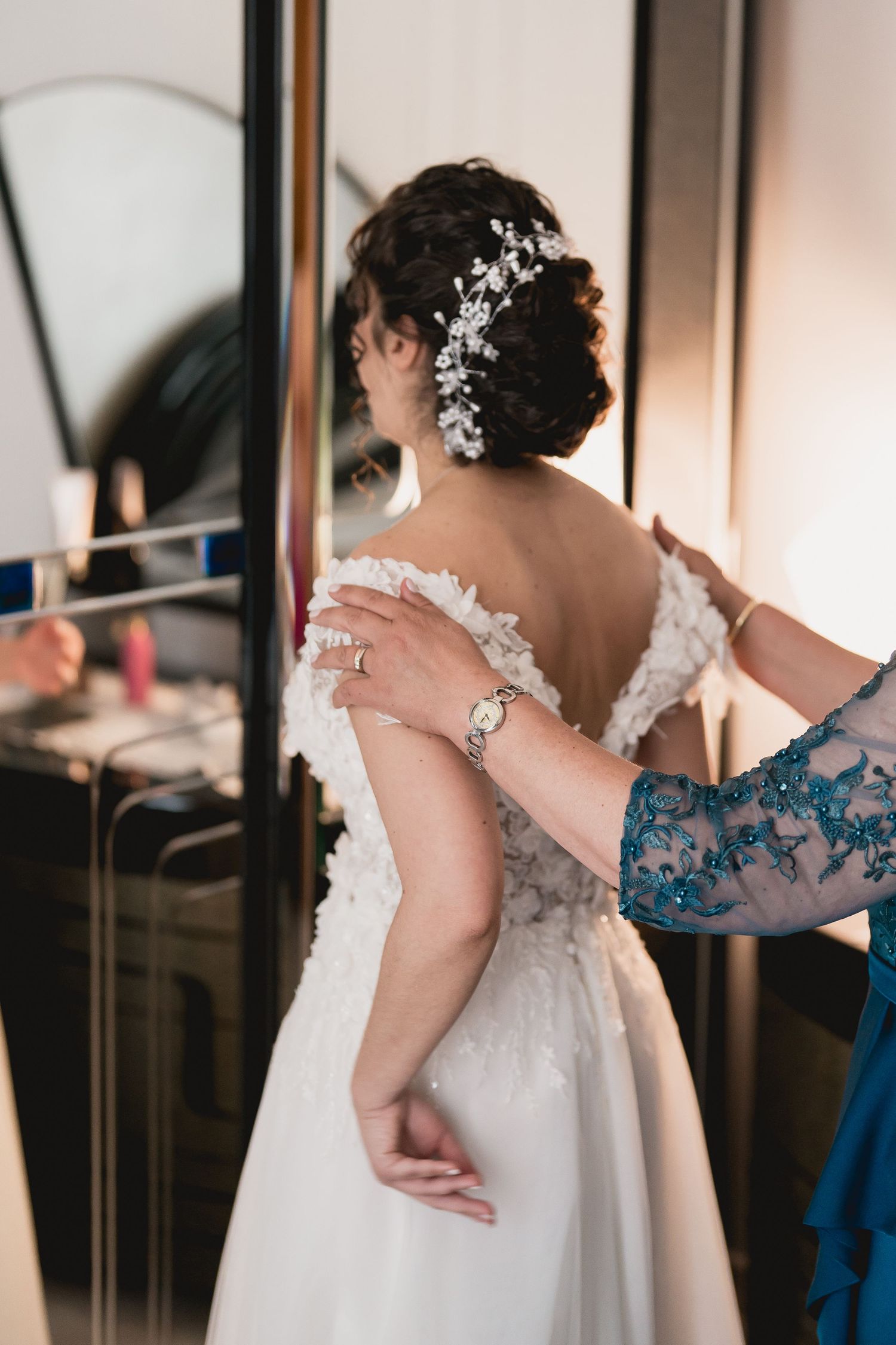 Close-up of a bride's back showing delicate lace dress details and floral hair accessories.