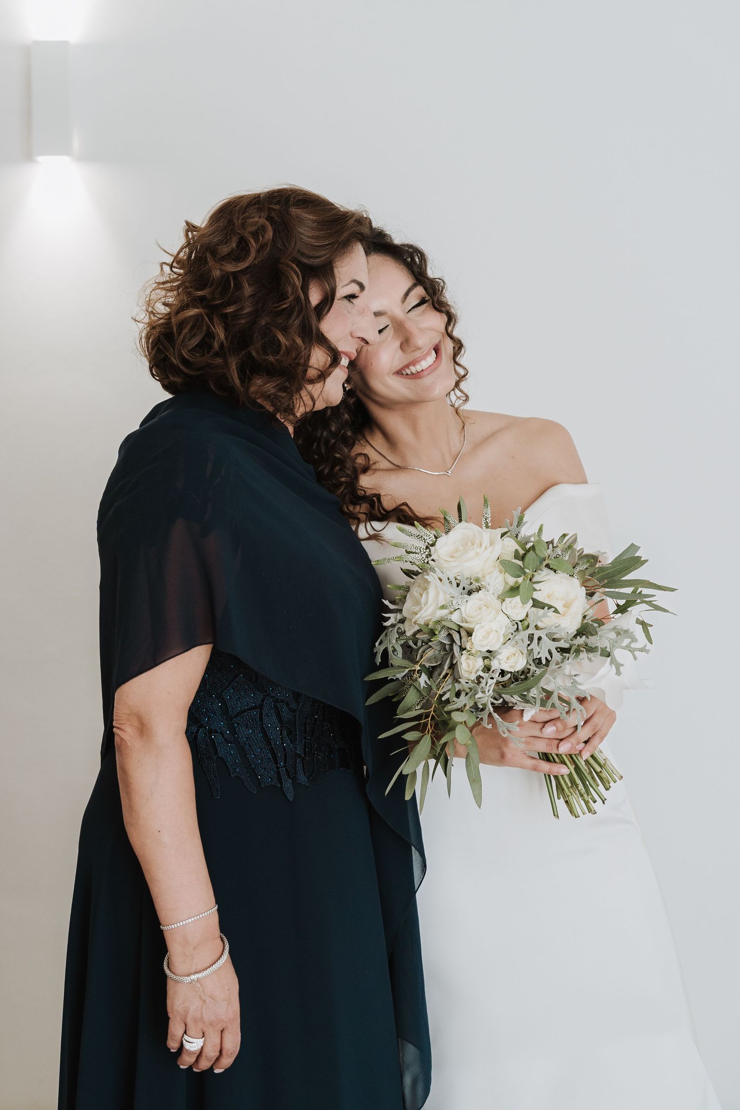 An intimate moment shared during wedding preparations with a white floral bouquet.